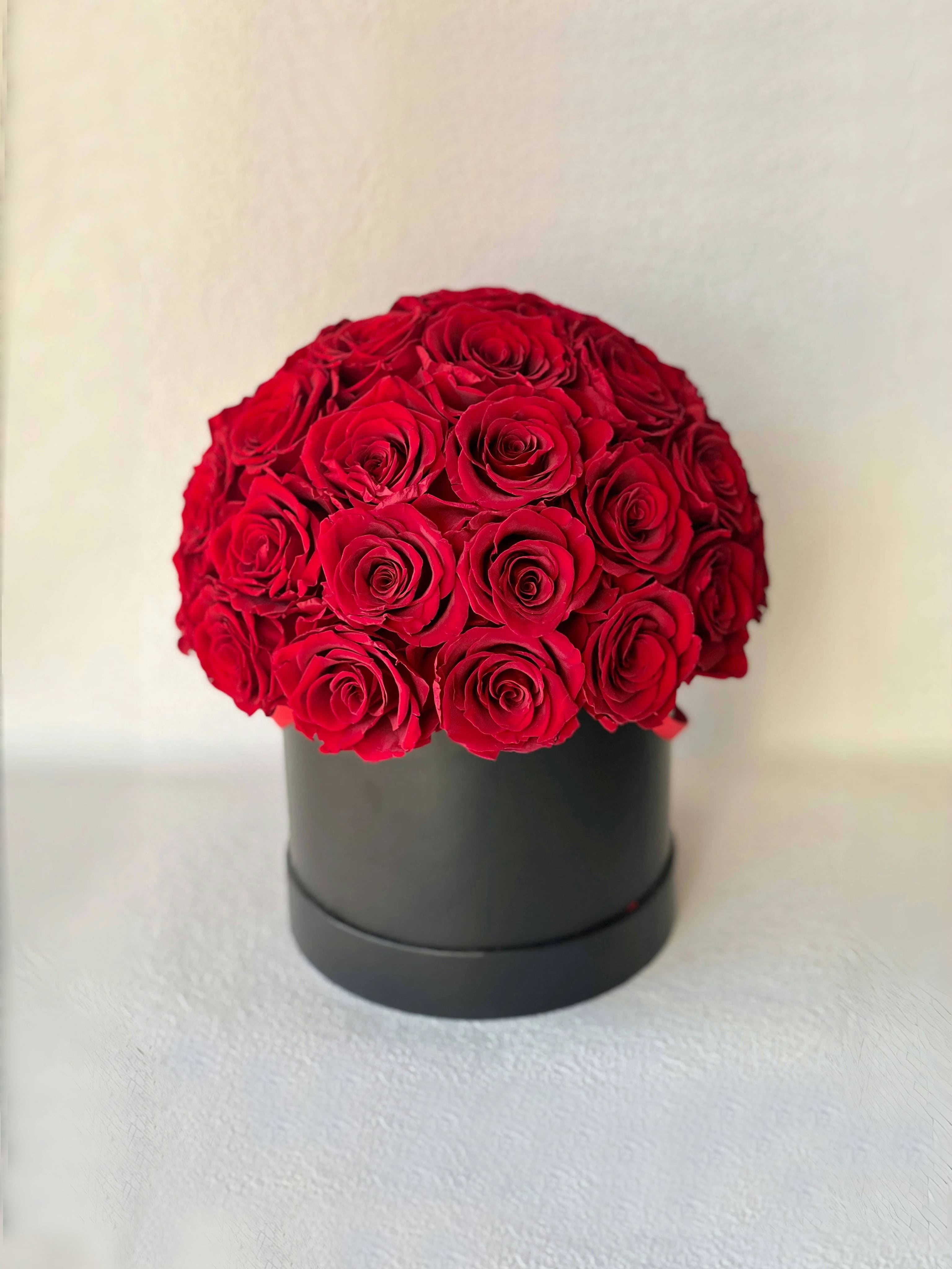 Stunning preserved red eternity rose arrangement in a sleek black hat box, ideal for special occasions or long-lasting home decoration.