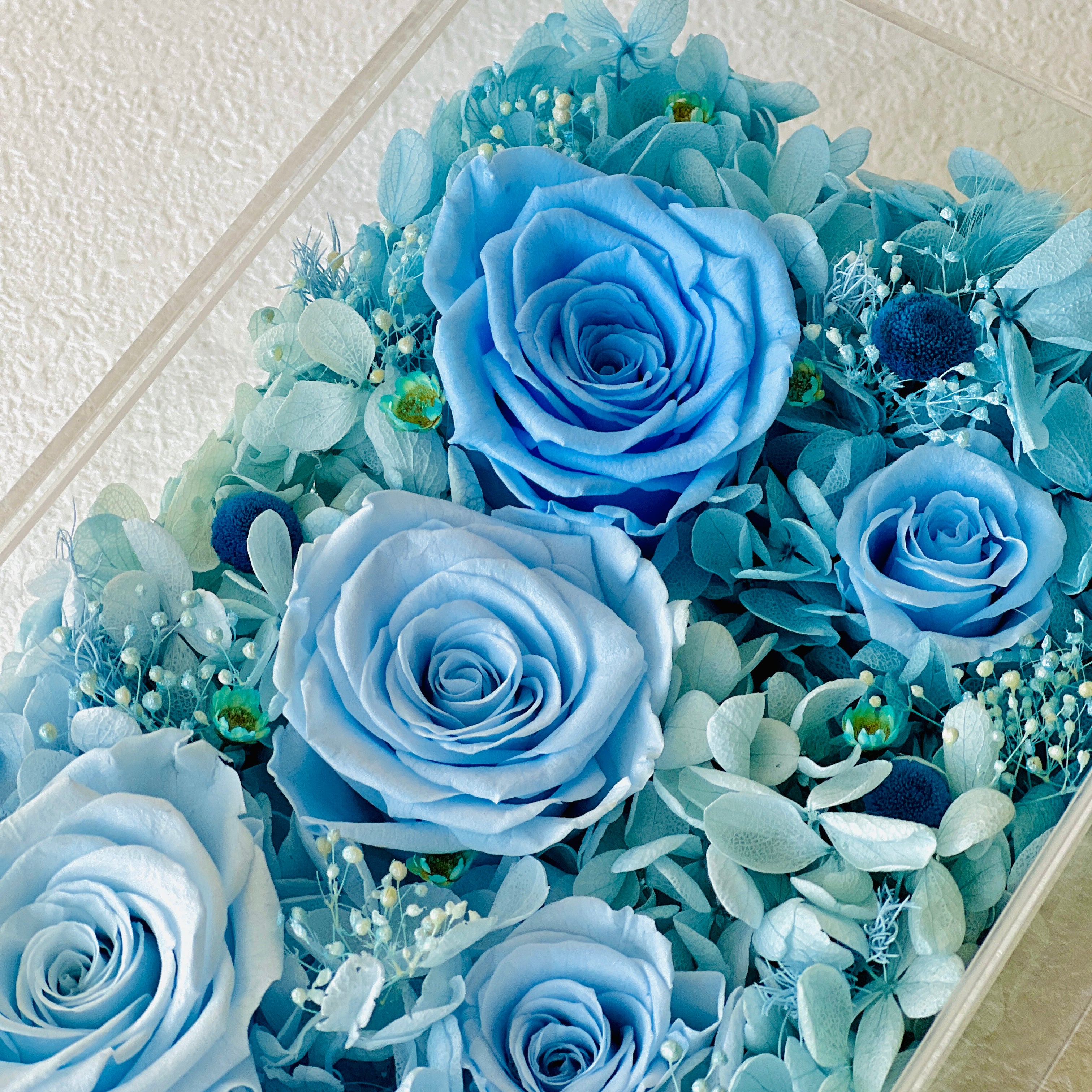 The Enchanted Rose Symphony features a mesmerizing gradient of preserved roses and hydrangeas, transitioning from soft blush pink to tiffany blue. A captivating eternity flower centerpiece for any space.