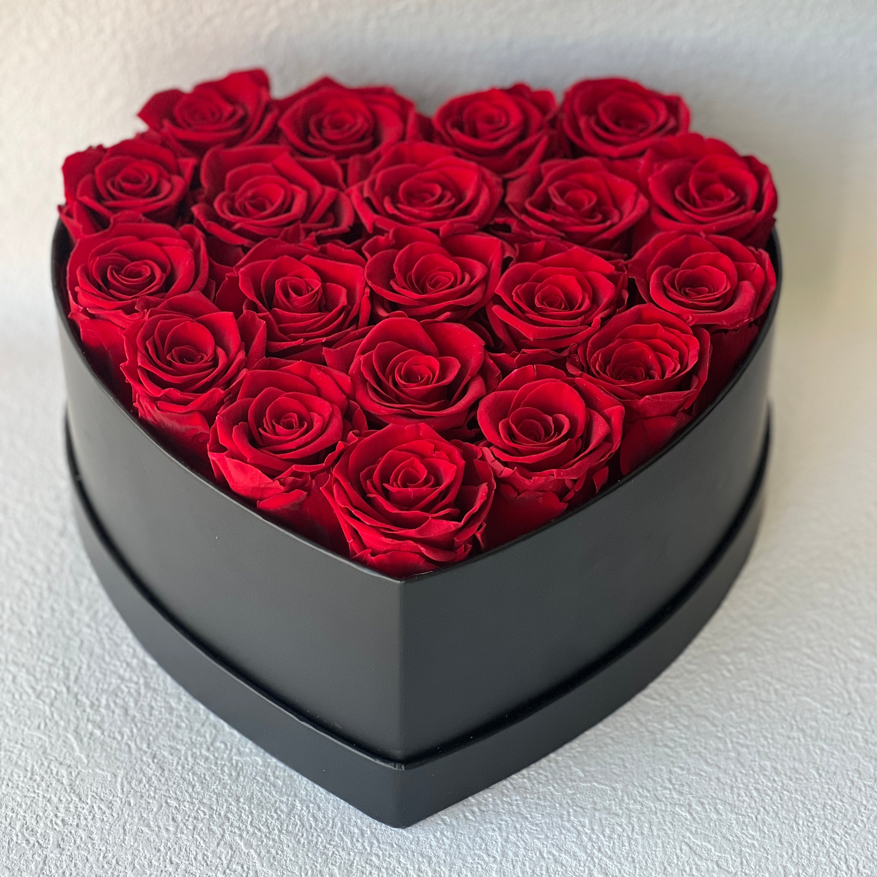 The Heart Hat Box With Roses features 20 Ecuadorian eternity red roses arranged in a black heart-shaped hatbox. This elegant and timeless rose gift lasts for 3-8 years, perfect for expressing love or adding a touch of sophistication to any space.