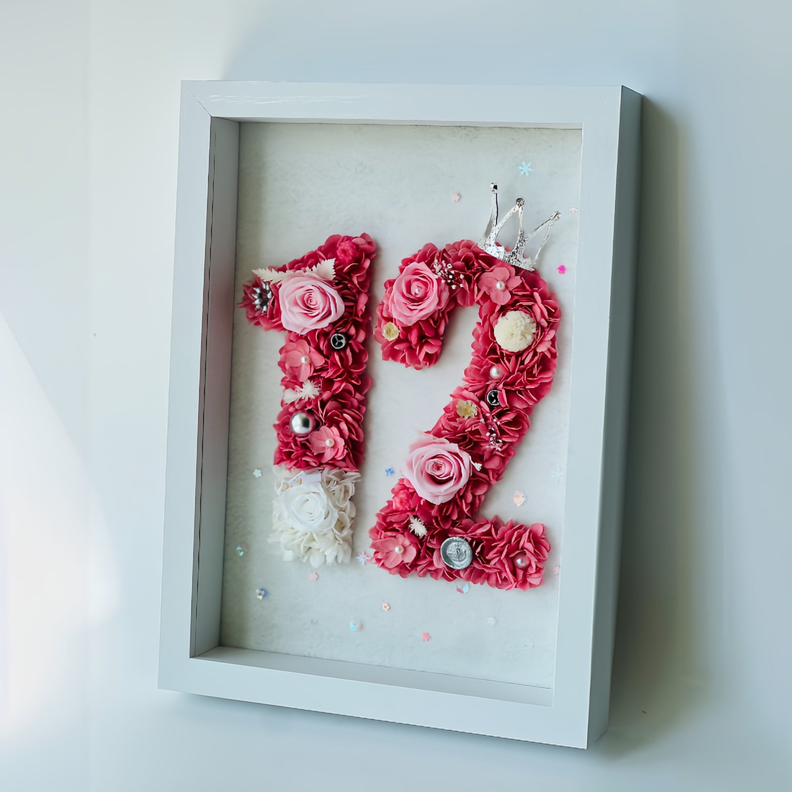 Custom number floral artwork featuring preserved roses and hydrangeas in pink hues, accented with sparkling embellishments and a tiara. Ideal for gifting or decor.