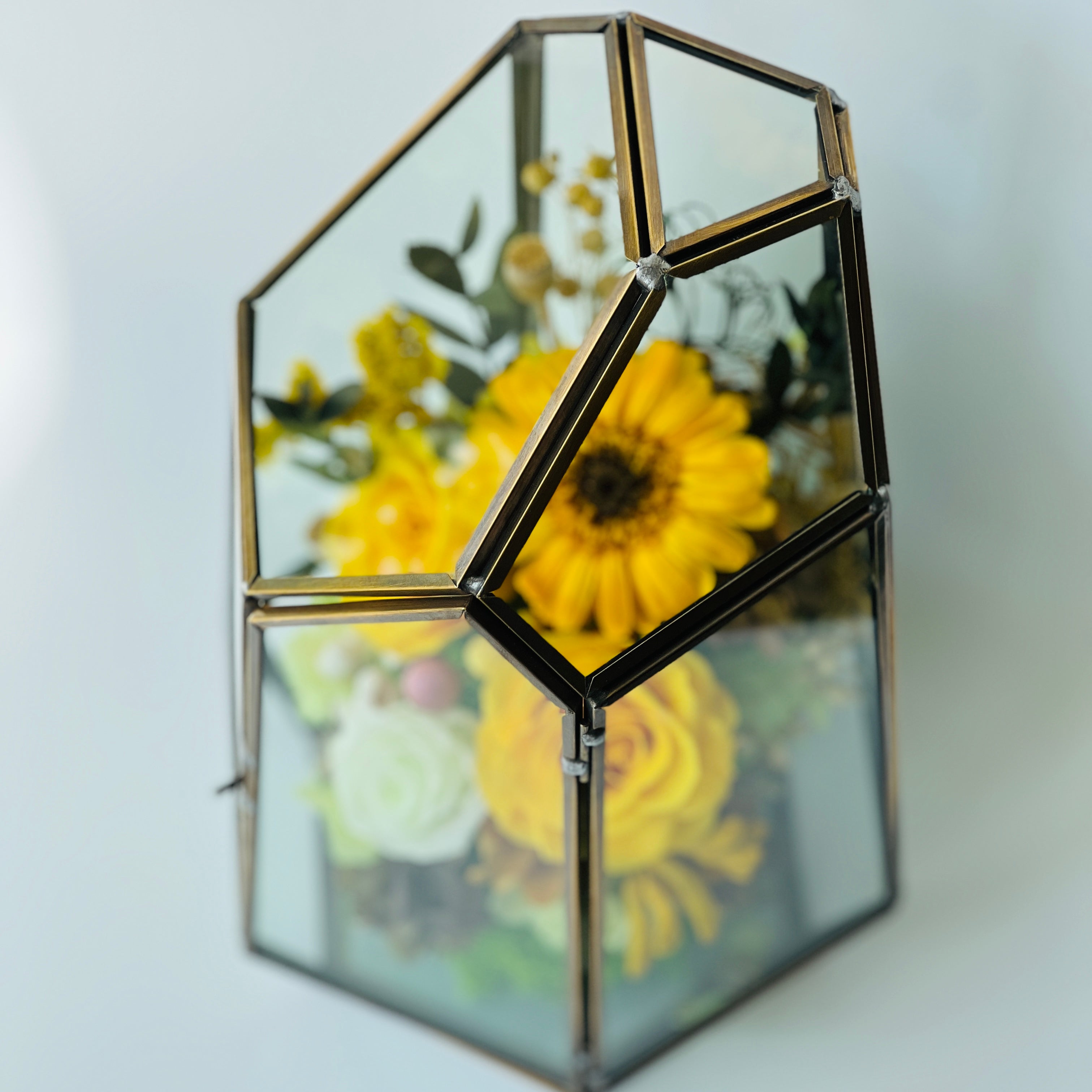 Sunshine and Serenity preserved floral arrangement featuring sunny yellow roses, a cheerful sunflower, and delicate white roses in a geometric acrylic terrarium. A perfect eternity rose gift to brighten any space.