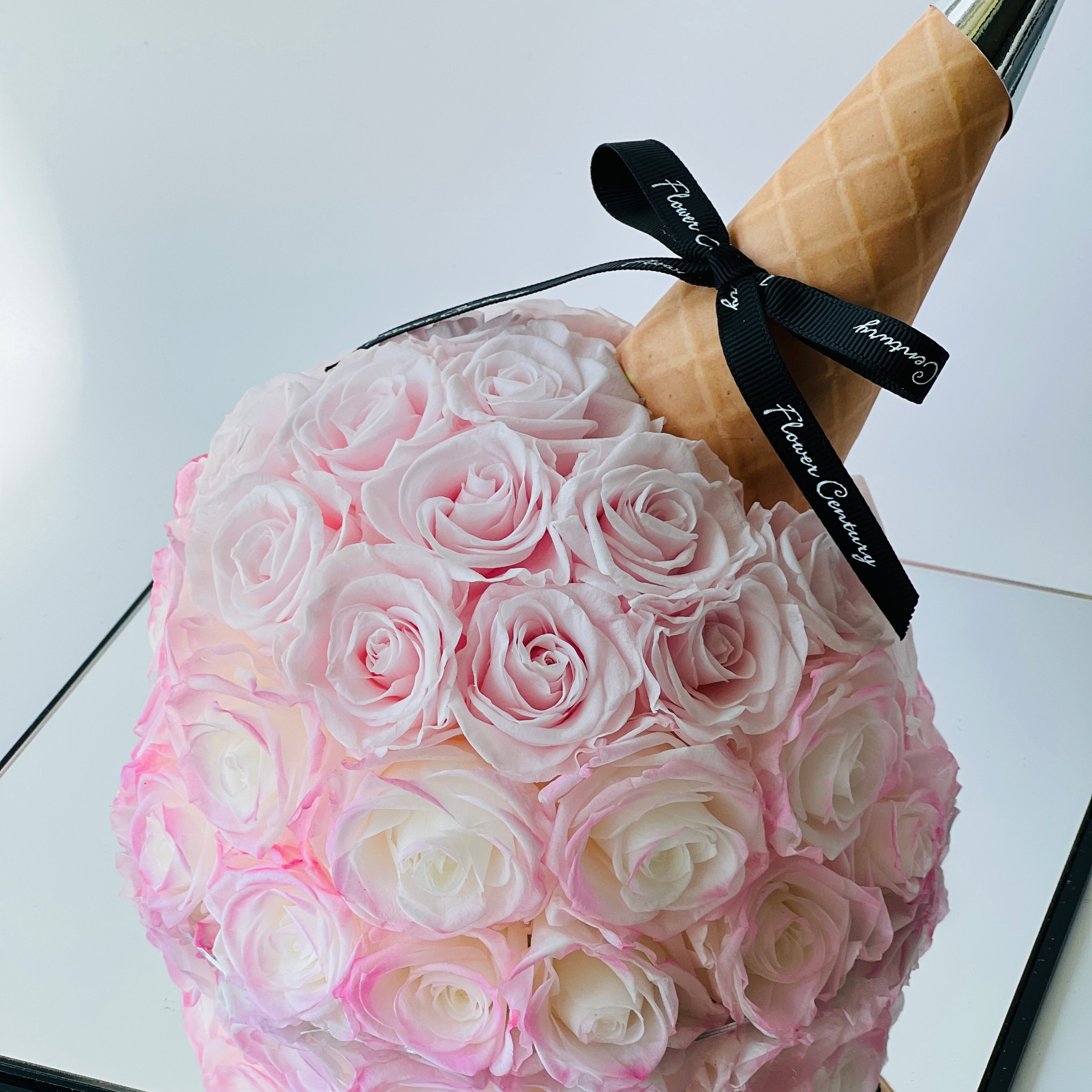 Whimsical Bouquet Cone featuring soft pink preserved roses in an ice cream cone-inspired wrap with a metallic tip. A playful and elegant eternity rose gift perfect for special occasions.