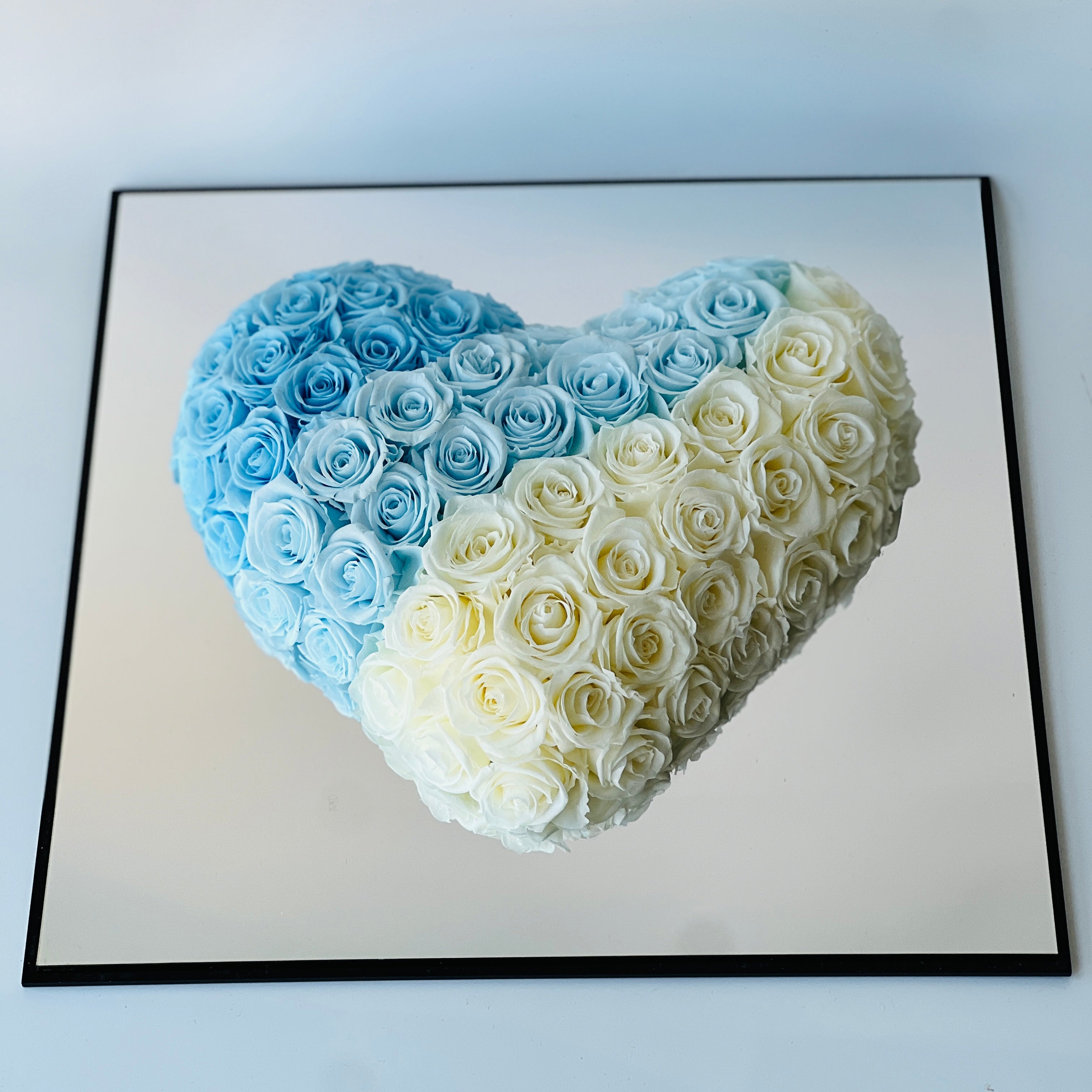 Heart-shaped arrangement of preserved roses in serene blue and white, symbolizing peaceful emotions. Perfect as a timeless eternity rose gift for special occasions.