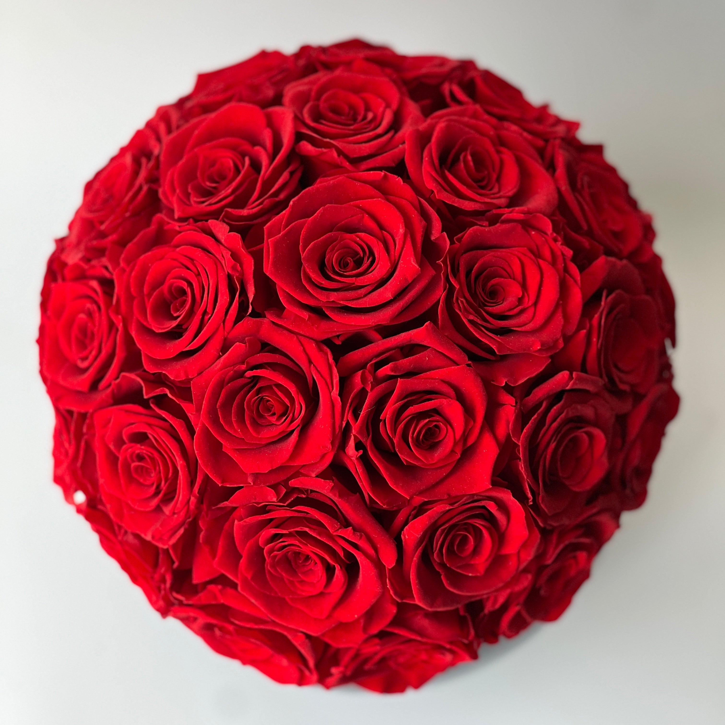 A sphere of preserved red roses in a glossy black vase, perfect for adding sophistication to any space. Maintenance-free and ideal for gifting.