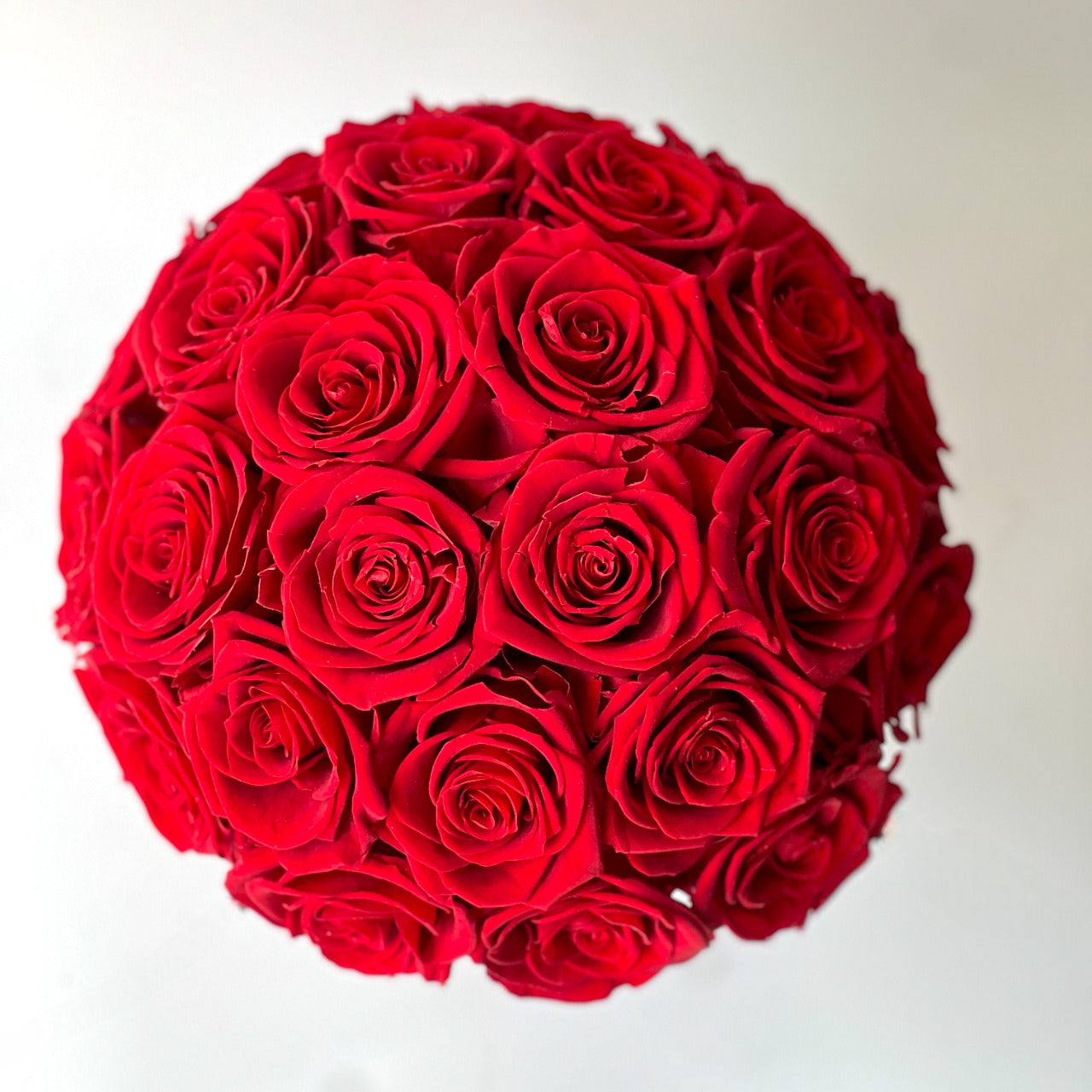 Elegant preserved red roses arranged on a two-tone pedestal vase. Maintenance-free and perfect as a dramatic centerpiece or memorable gift.