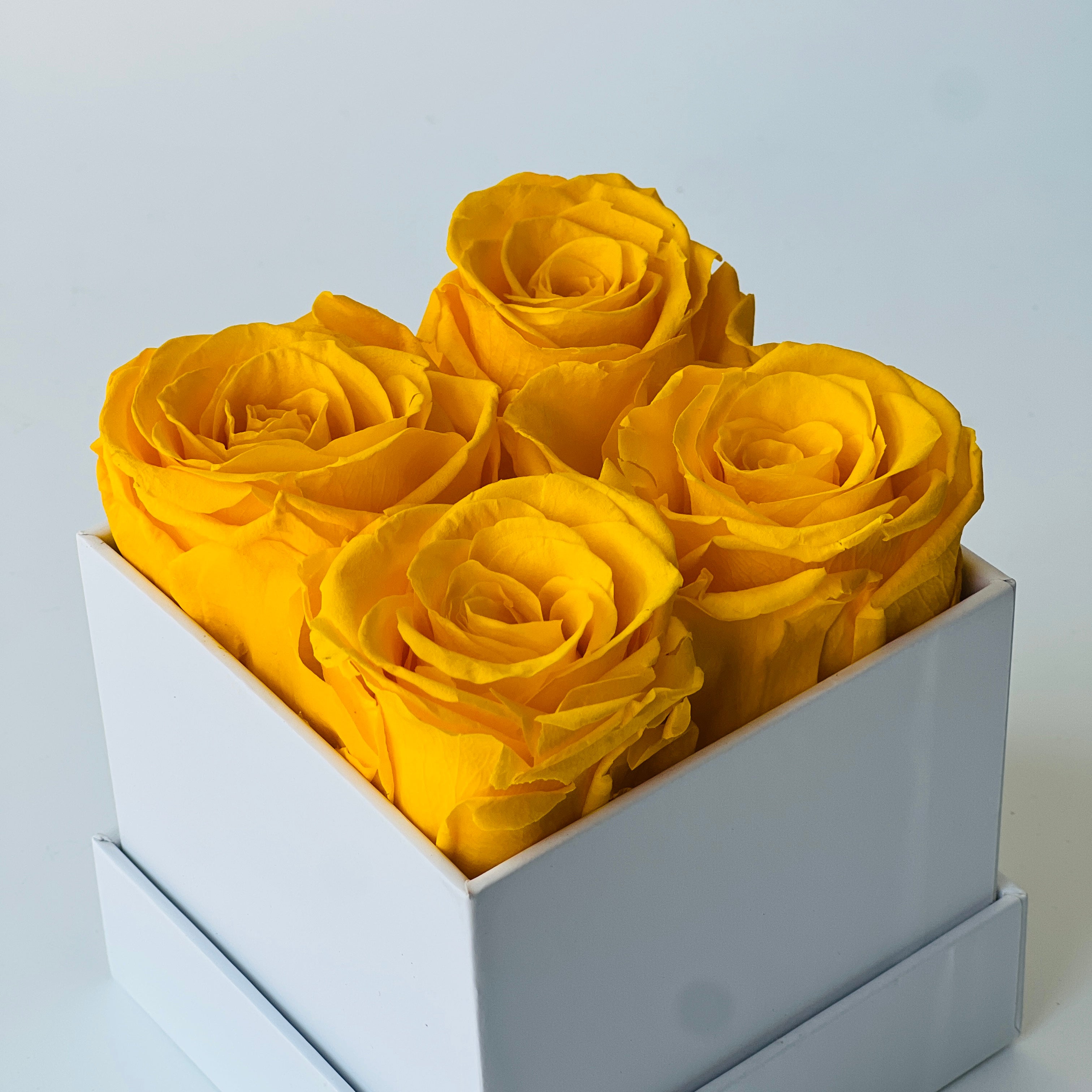 The Sunshine Roses arrangement features vibrant yellow preserved roses in a minimalist white box, offering a burst of joy and lasting beauty. This cheerful eternity rose gift is perfect for brightening any space or as a thoughtful gesture for any occasion.