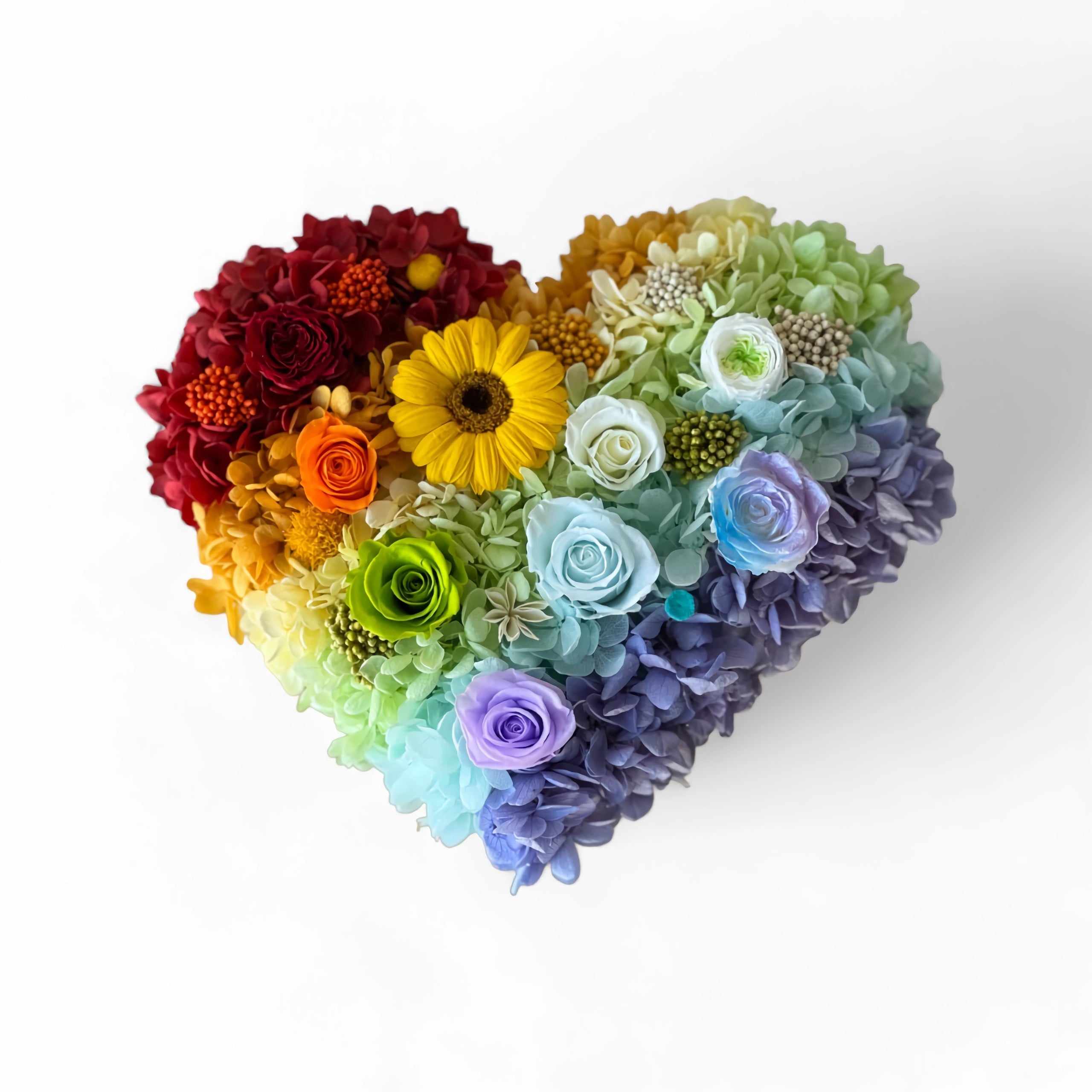 The Rainbow Heart Floral Box features vibrant preserved roses, a sunflower, and hydrangeas arranged in a heart shape. This charming eternity rose gift is perfect for special occasions like Valentine's Day or anniversaries.