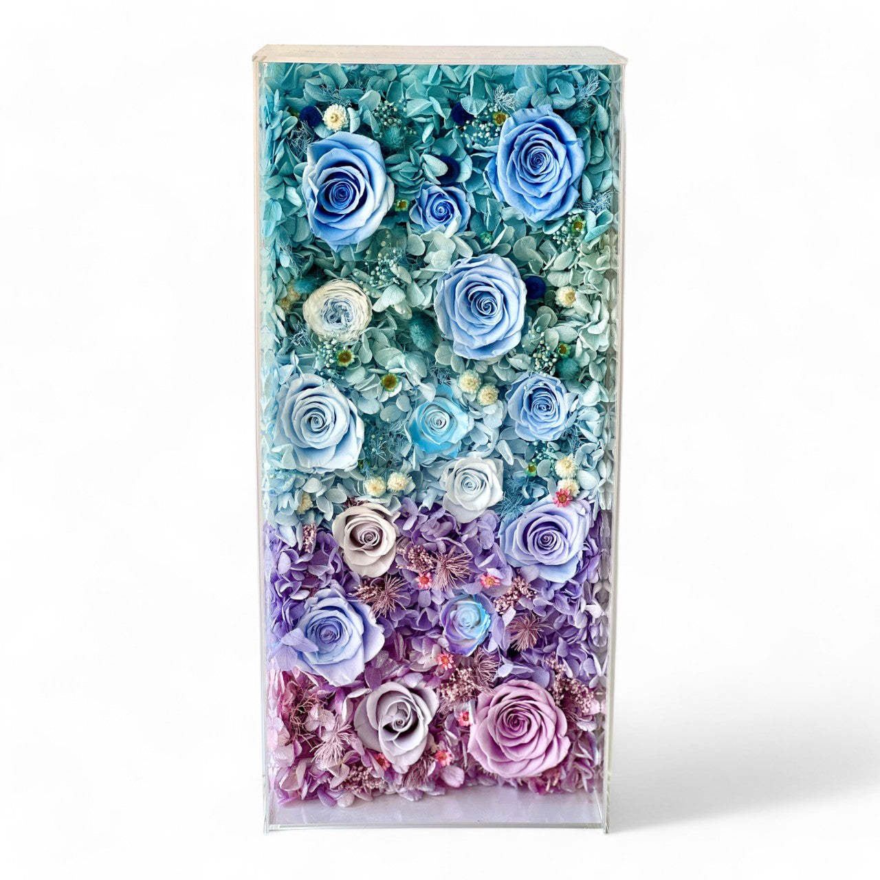 The Enchanted Rose Symphony showcases a stunning gradient of preserved roses and hydrangeas, blending soft blush pink, lavender, and tiffany blue hues. This eternity flower arrangement is a perfect centerpiece for any occasion.