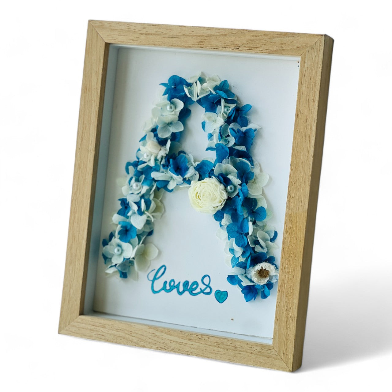 Preserved floral letter display featuring blue and white hydrangeas, accented with pearls and a white rose. Perfect for personalized gifting or home decor.