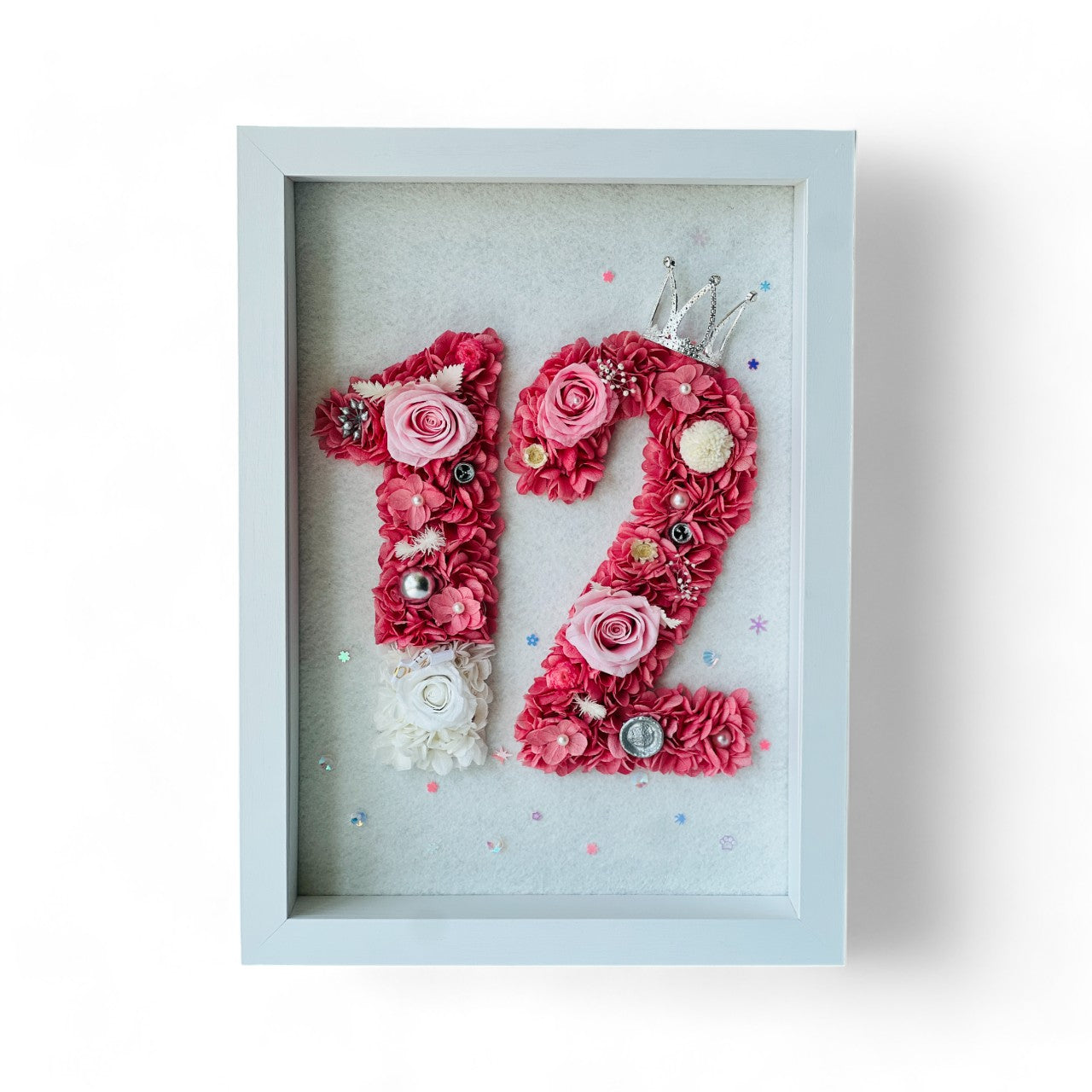 Custom number floral artwork featuring preserved roses and hydrangeas in pink hues, accented with sparkling embellishments and a tiara. Ideal for gifting or decor.