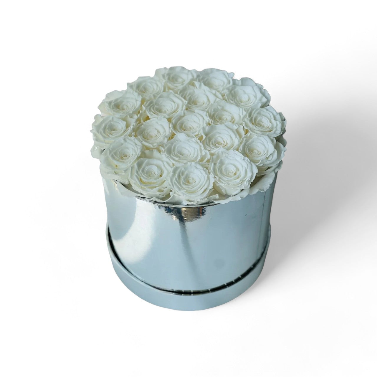 The White Rose Hatbox features preserved white roses elegantly arranged on a reflective silver base, offering a statement of purity and luxury. This timeless eternity rose gift is ideal for adding a serene and classic touch to any space, perfect for special occasions.