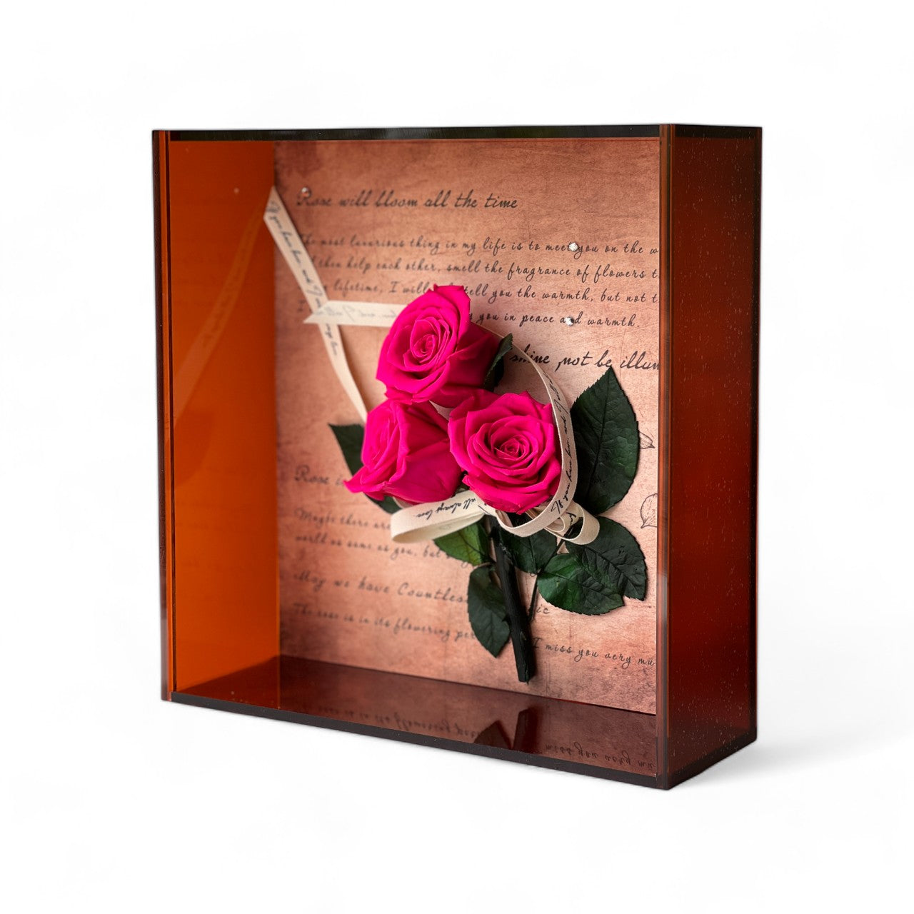 Elegant preserved pink roses arranged against a handwritten script backdrop, wrapped in vintage ribbon and encased in a deep copper frame. A timeless eternity rose gift perfect for special occasions.