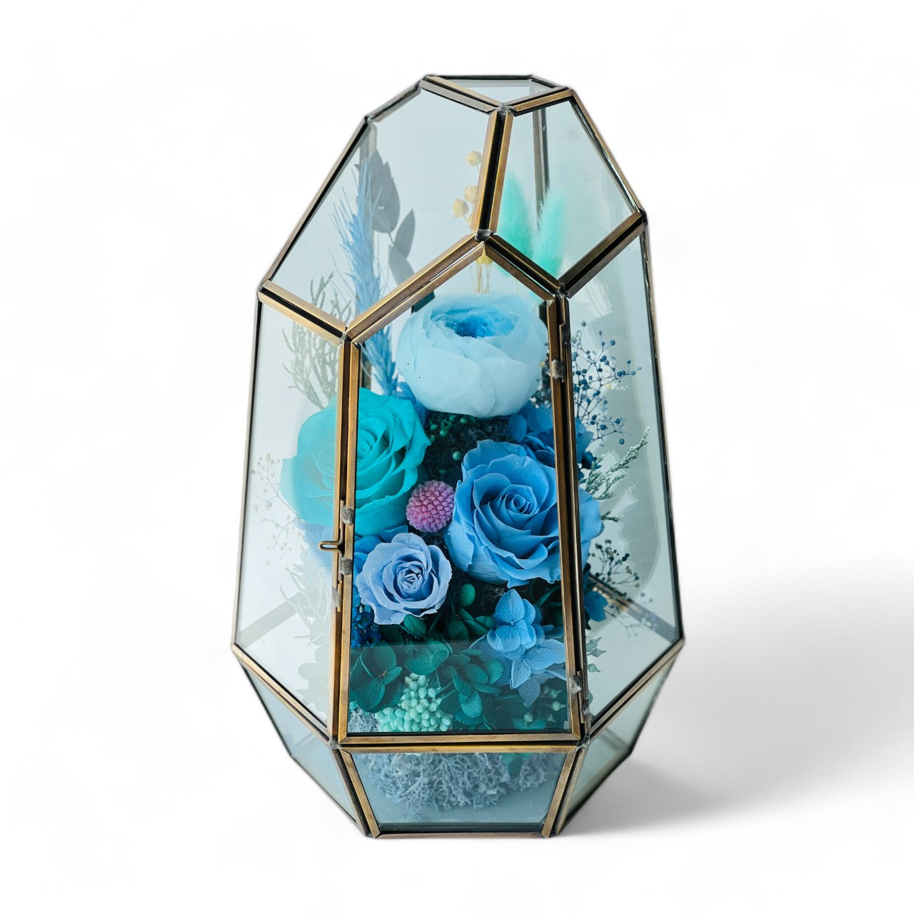 Exquisite Ocean Breeze preserved floral terrarium featuring deep ocean blue roses and hydrangeas, accented with greenery and pink florals in a modern geometric vessel. Perfect as a timeless eternity rose gift.