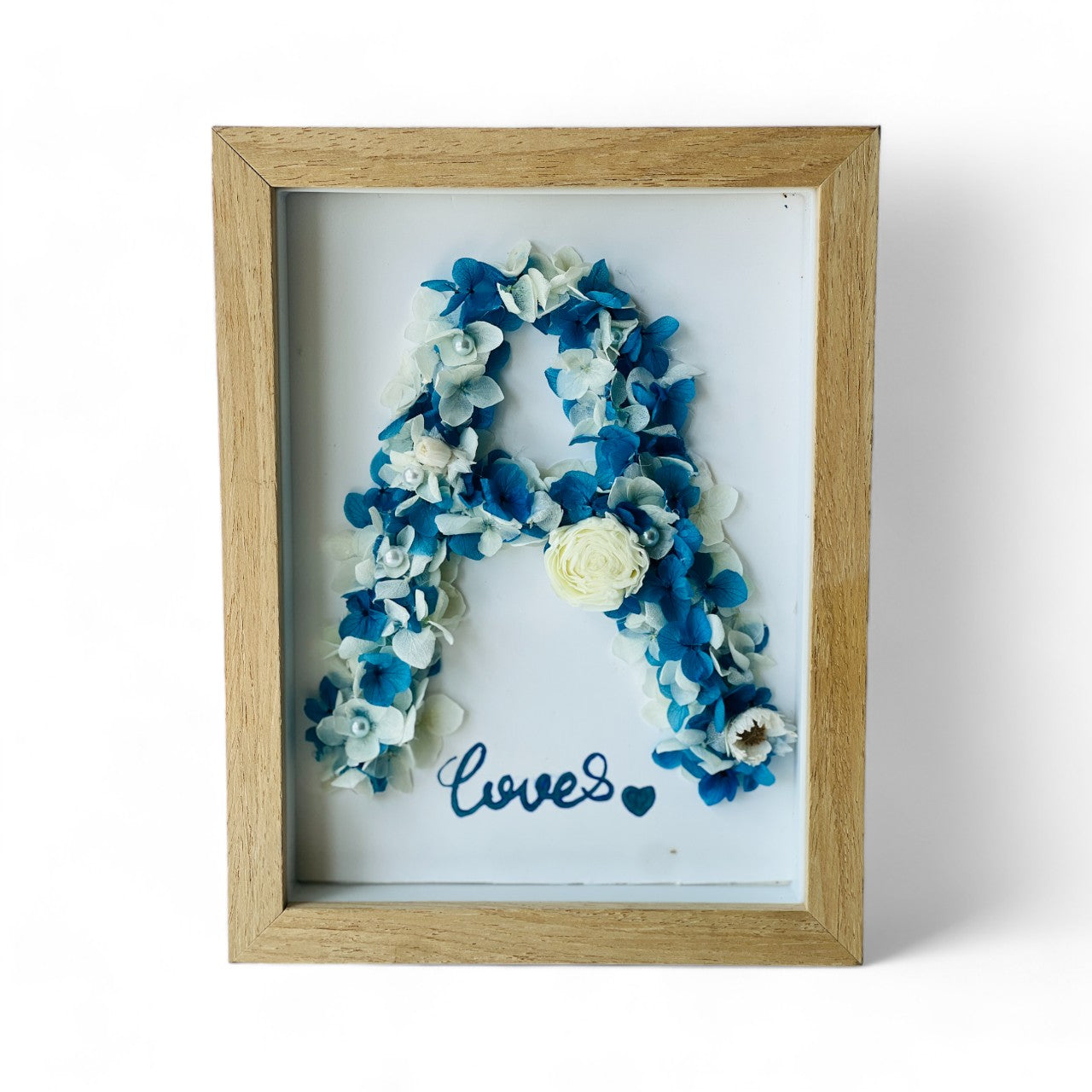 Preserved floral letter display featuring blue and white hydrangeas, accented with pearls and a white rose. Perfect for personalized gifting or home decor.