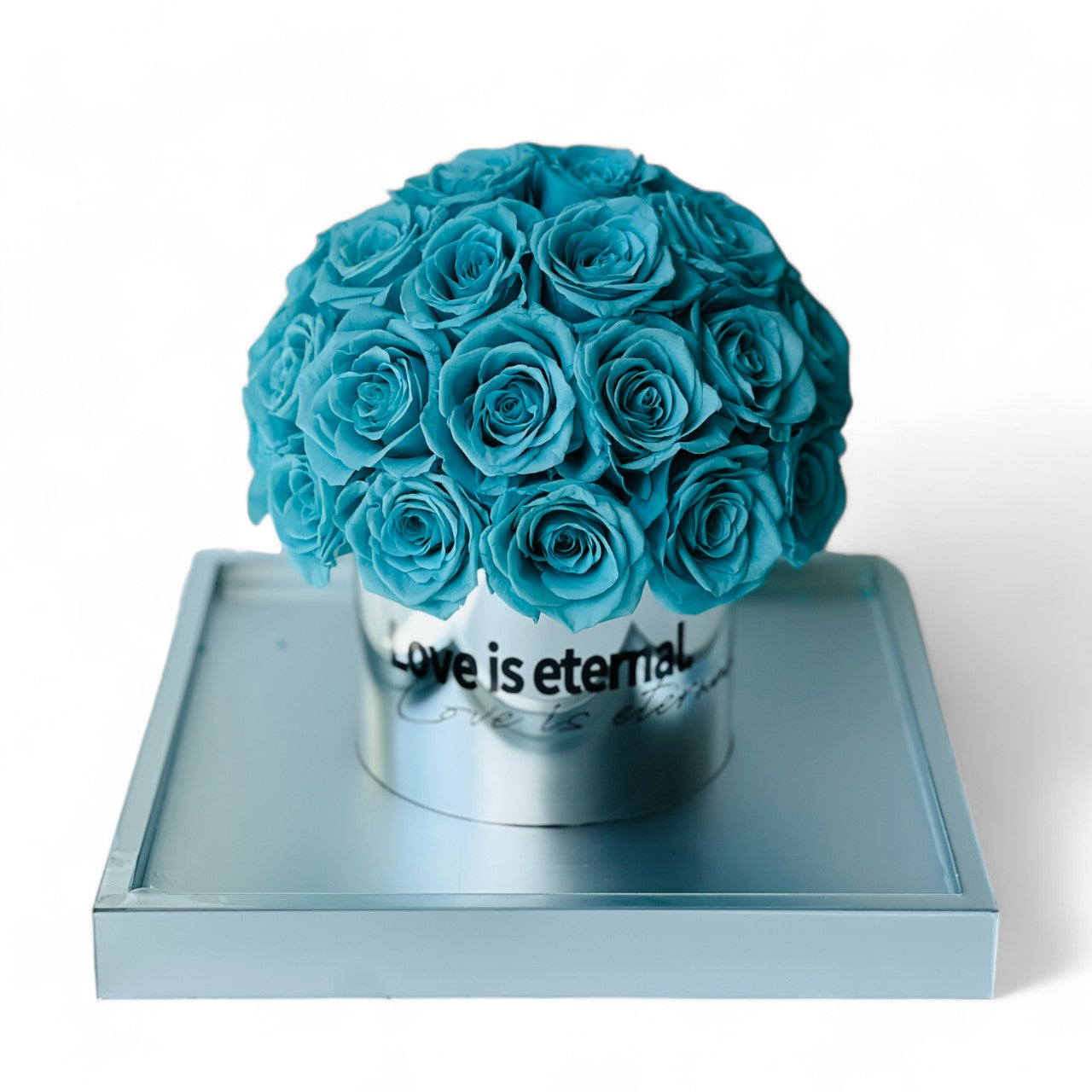 The Tiffany Blue Rose Hatbox features preserved roses on a sleek grey base inscribed with "love is eternal." This serene eternity rose arrangement offers a modern statement of enduring affection, perfect for adding tranquility to any space or as a heartfelt gift.