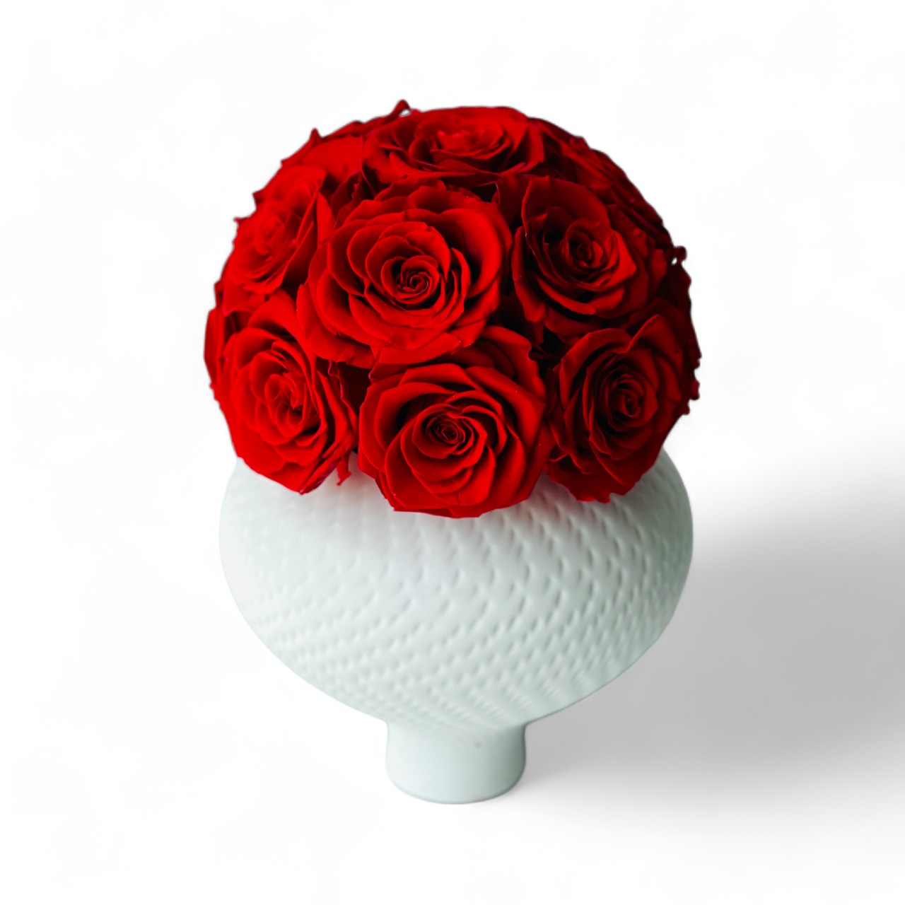 Deep red preserved roses in a textured white vase create a striking, elegant centerpiece. Maintenance-free and perfect for adding lasting beauty to any space.