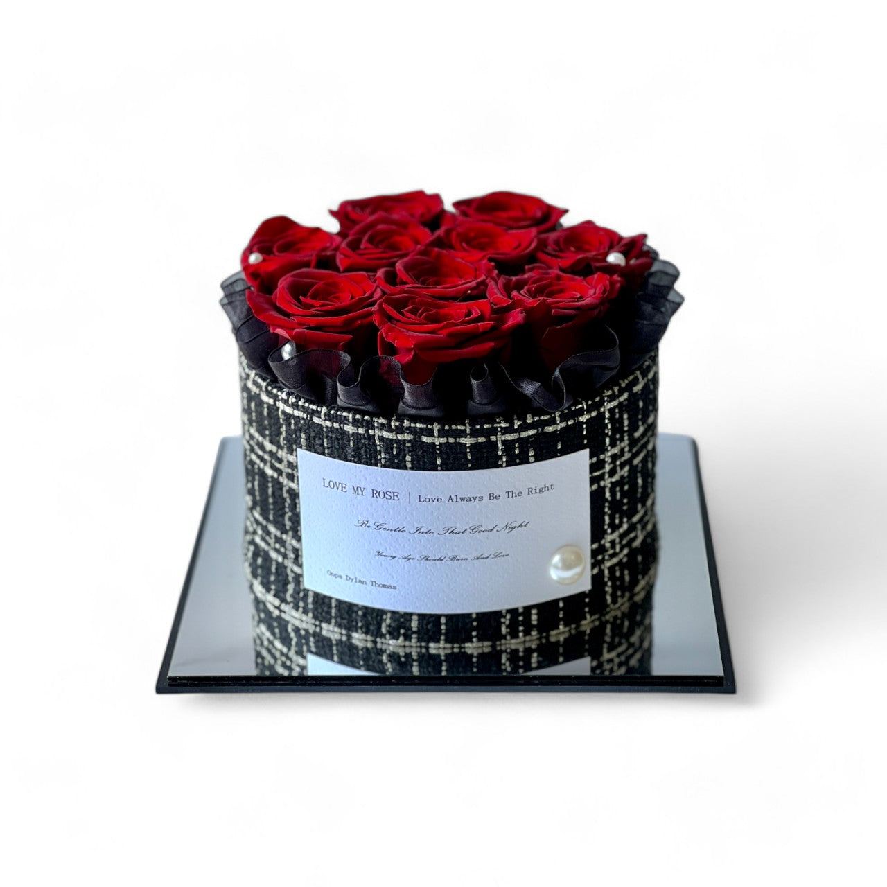 The Crimson Elegance preserved flower arrangement features deep red roses encased in a luxurious black and white patterned box, adorned with pearl accents. A timeless eternity rose gift, perfect for adding romance and sophistication to any space.