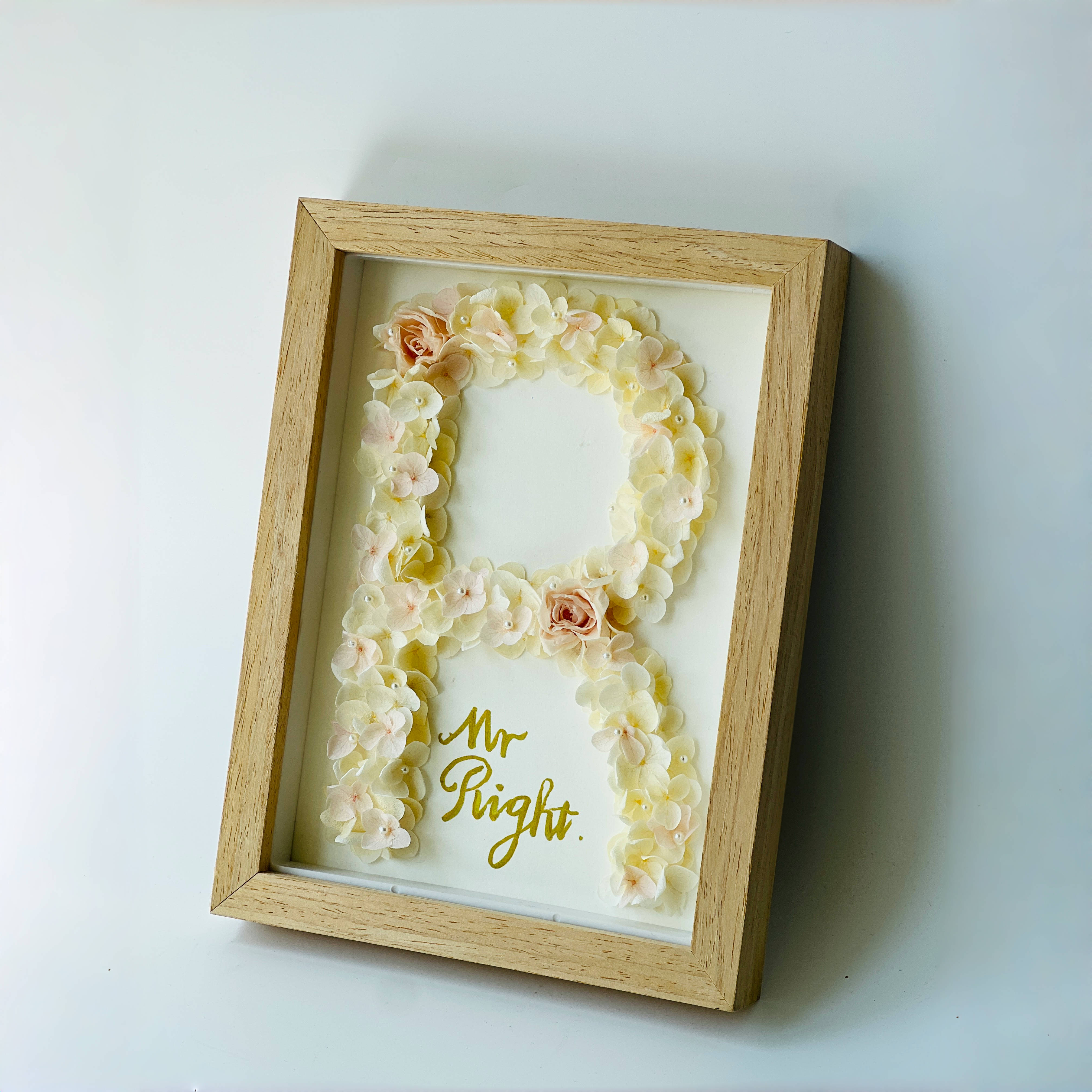 Charming preserved floral letter art with roses and hydrangeas, framed in wood, perfect for gifting or decorating with a poetic touch.