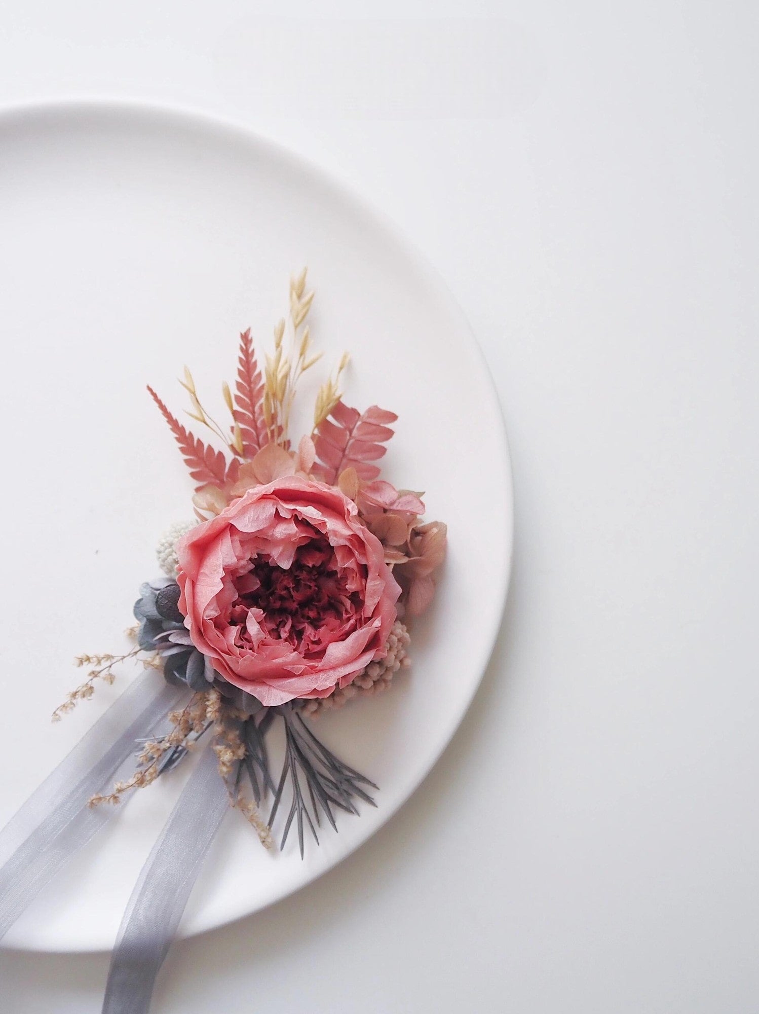 Dusty rose peony corsage with fern accents for weddings.
