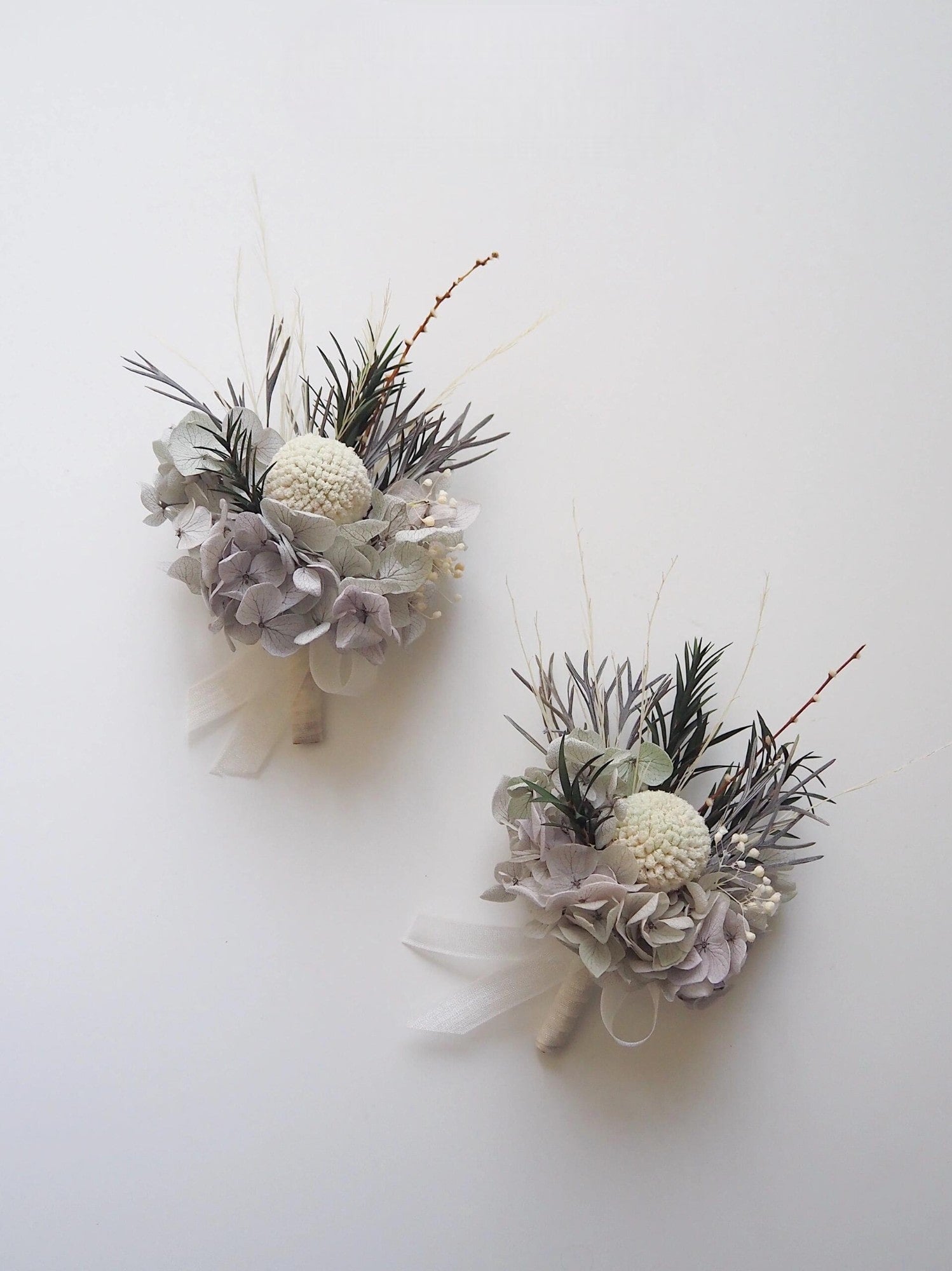 Elegant boutonniere featuring gray hydrangeas and ivory centerpiece.
