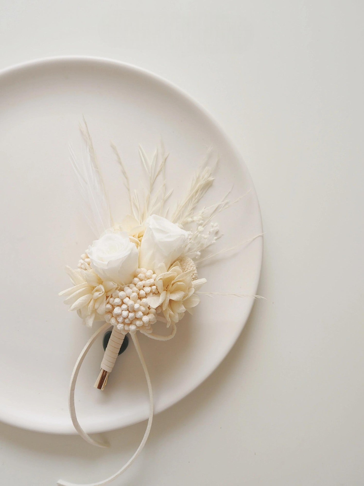 Elegant wedding boutonniere with preserved ivory roses and pearls
