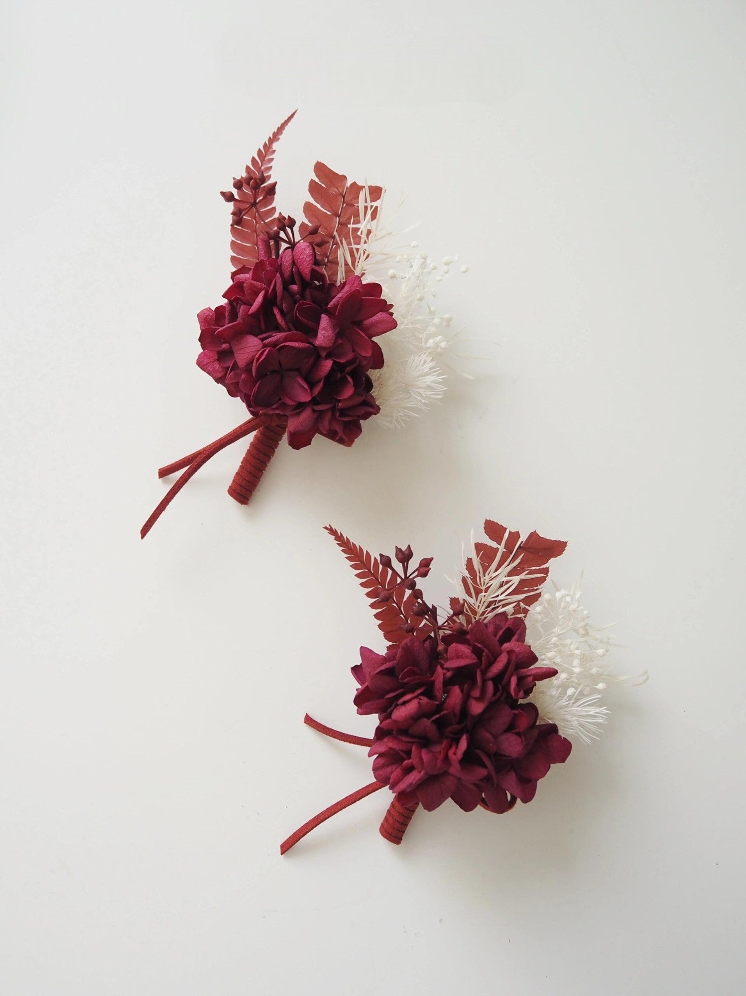 Elegant wedding boutonniere with preserved burgundy hydrangeas and ferns
