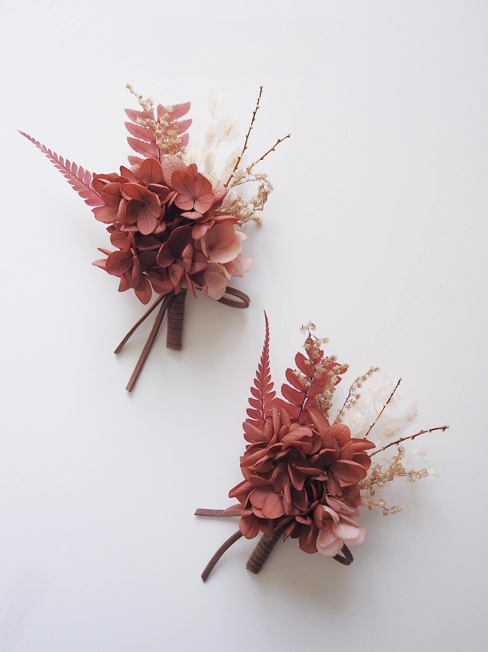 Elegant rust-colored boutonniere with preserved flowers and ferns
