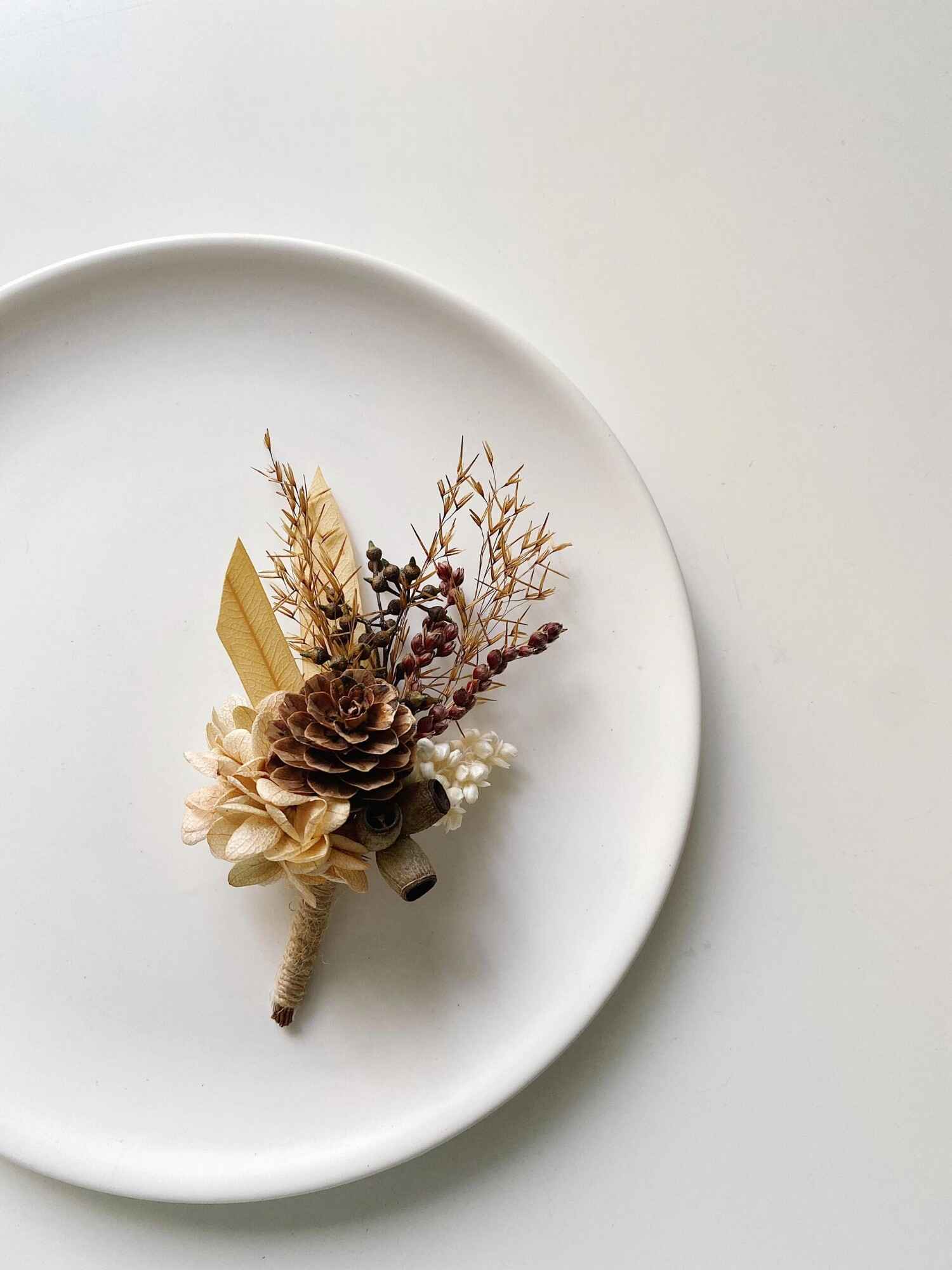 Handmade boutonniere with natural pinecone and dried accents.
