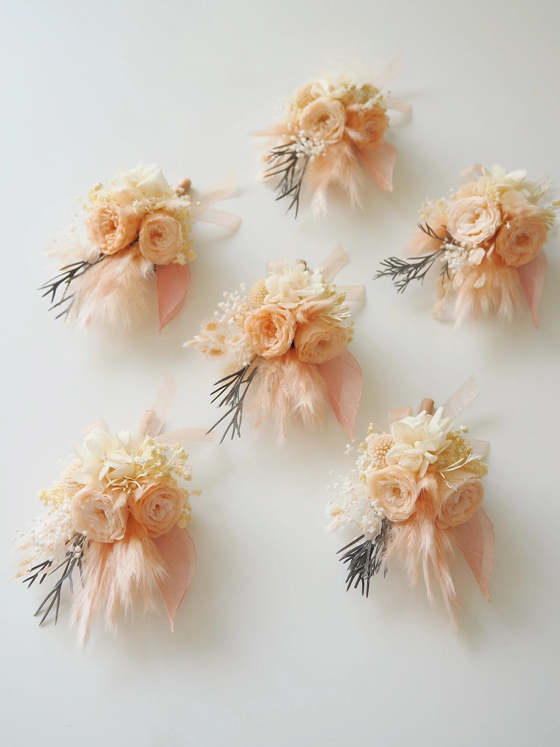 Rustic wedding boutonniere featuring peach ranunculus and pampas grass
