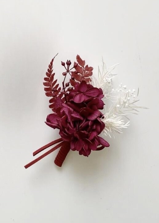 Preserved flower boutonnieres featuring terracotta hydrangeas and white accents
