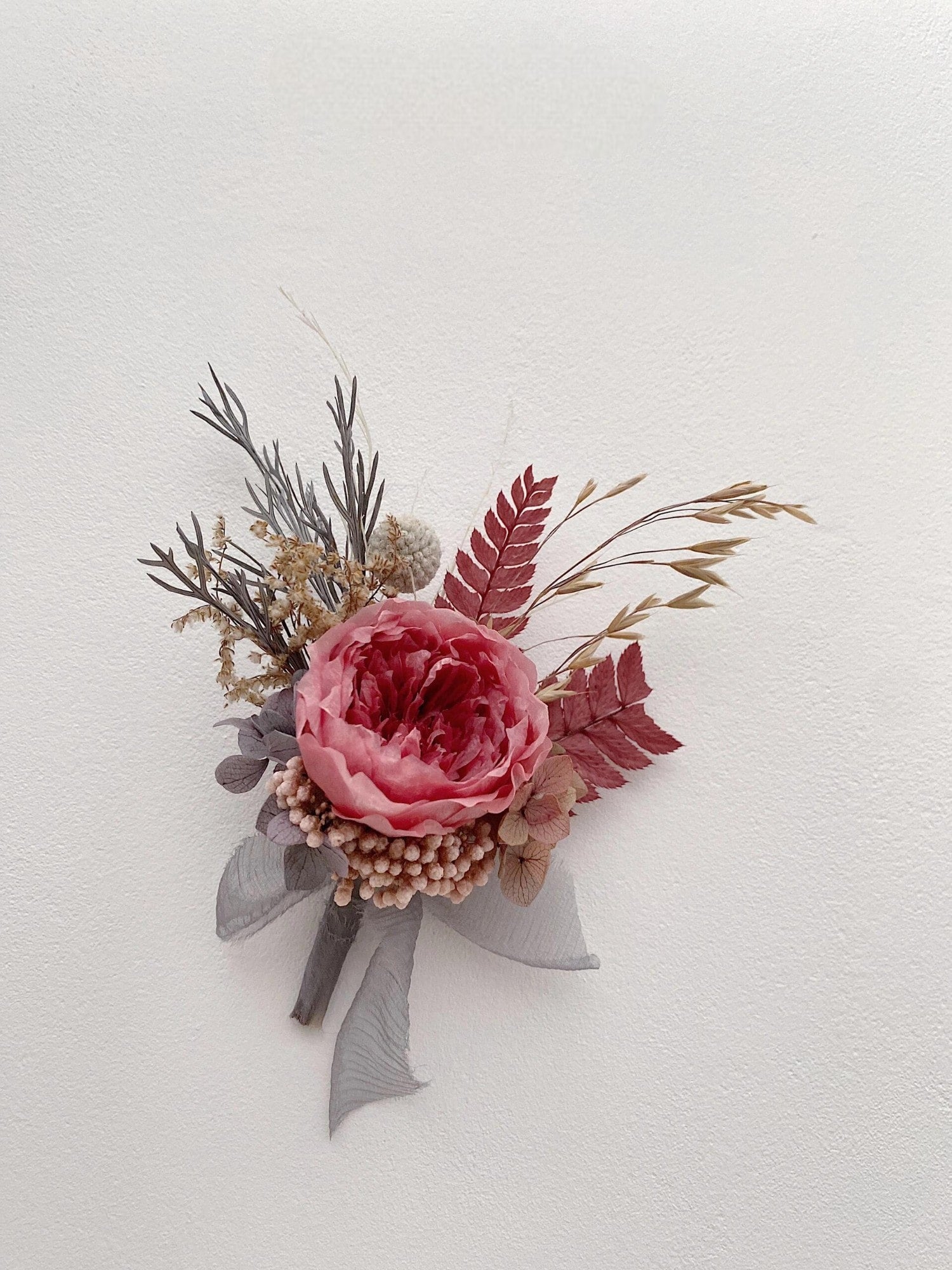 Wedding boutonniere with preserved flowers in dusty rose tones
