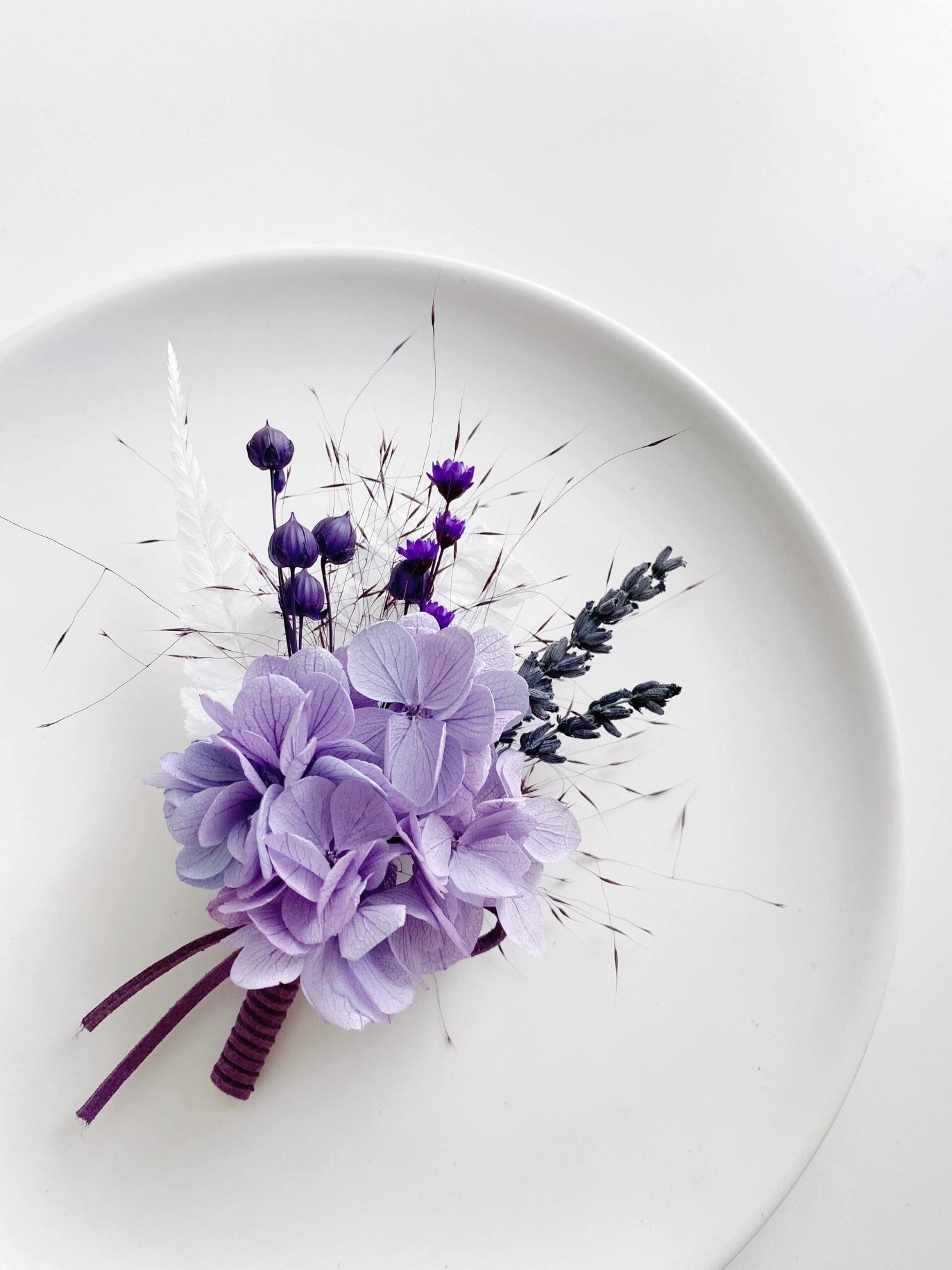 Close-up of lavender hydrangea boutonniere with dark purple accents.
