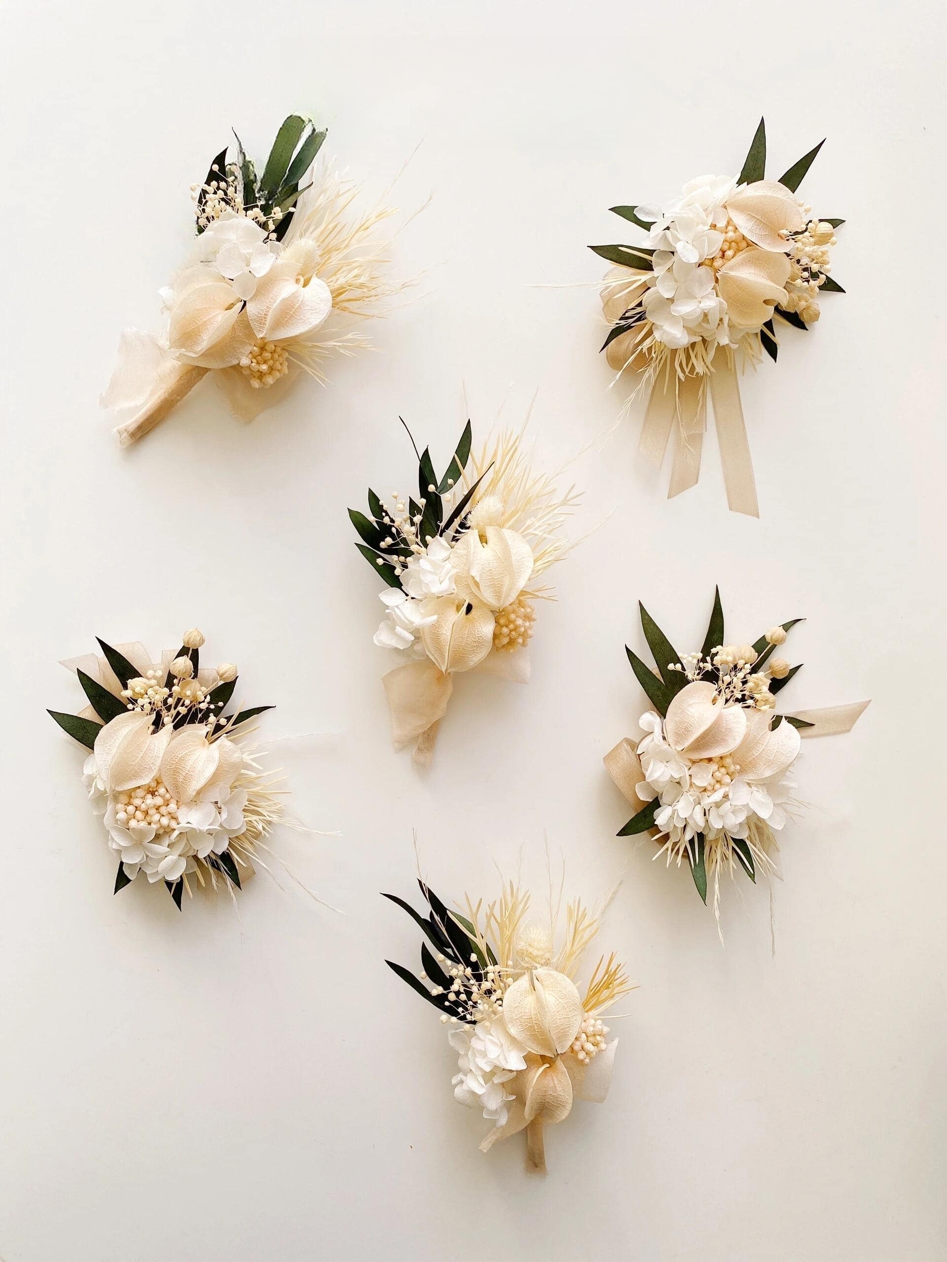 Ivory calla lily boutonniere with white hydrangea and green leaves
