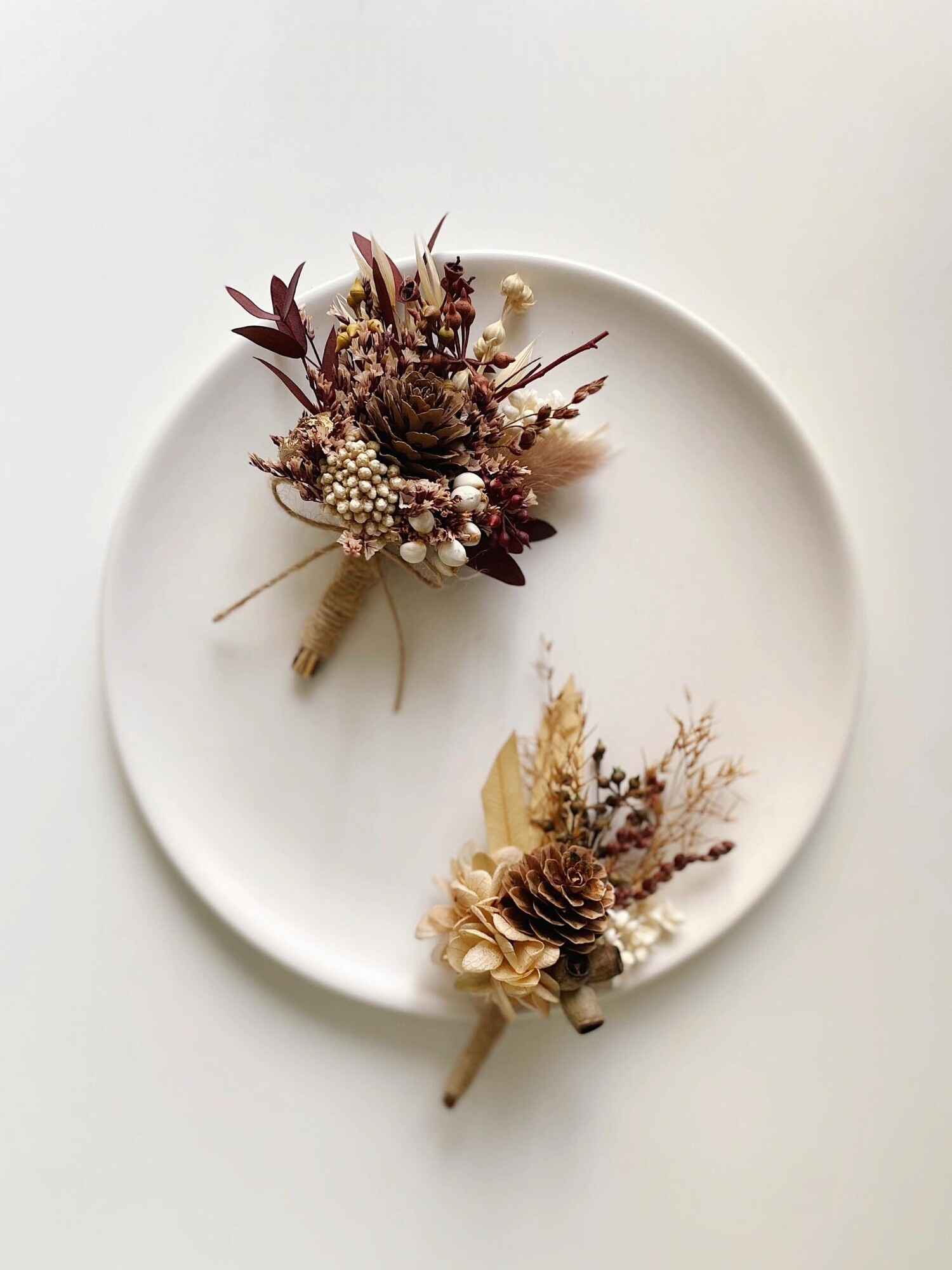 Close-up of pinecone boutonniere with dried flowers and leaves.
