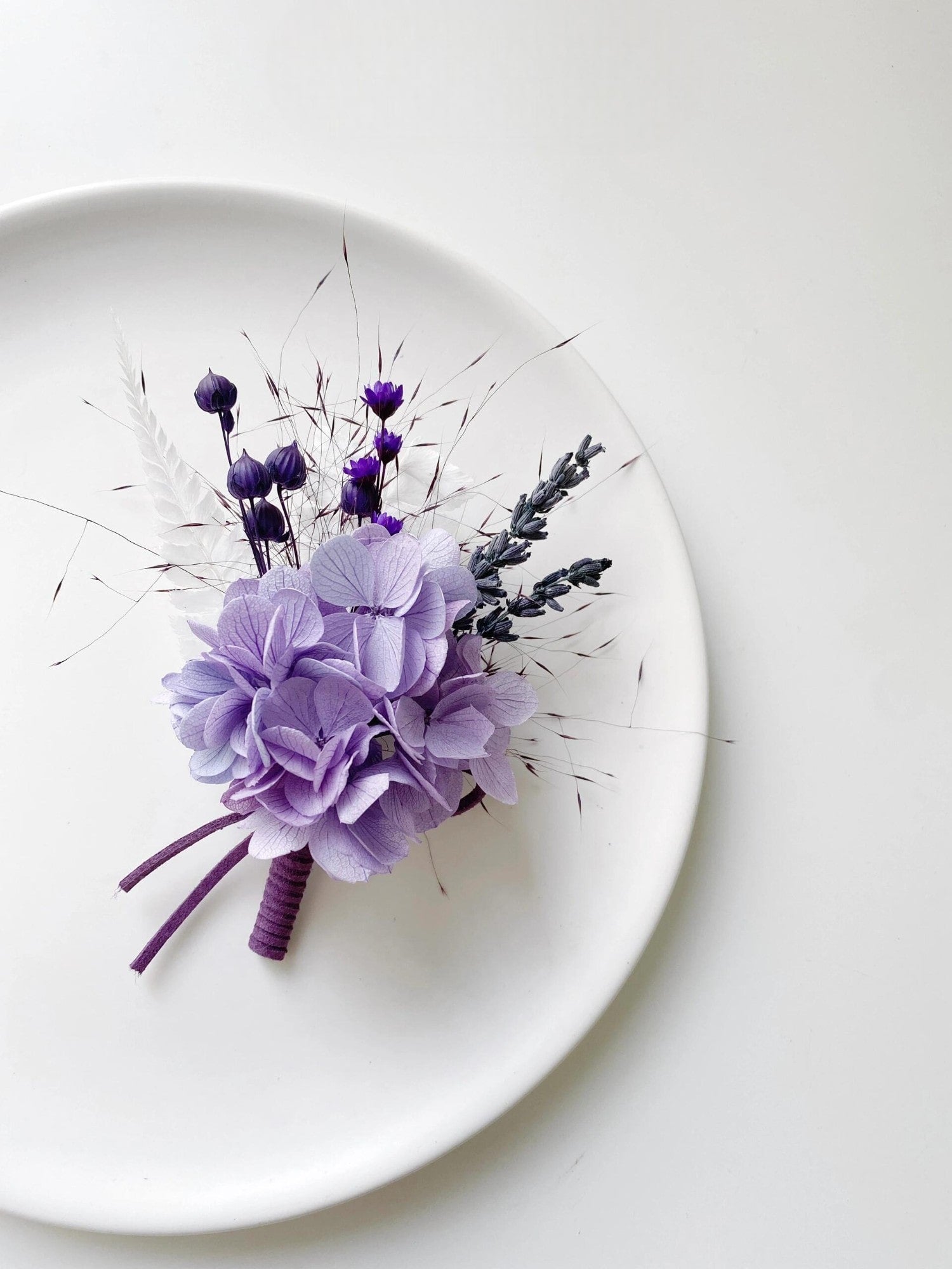 Floral boutonniere with lavender hydrangea and purple buds.
