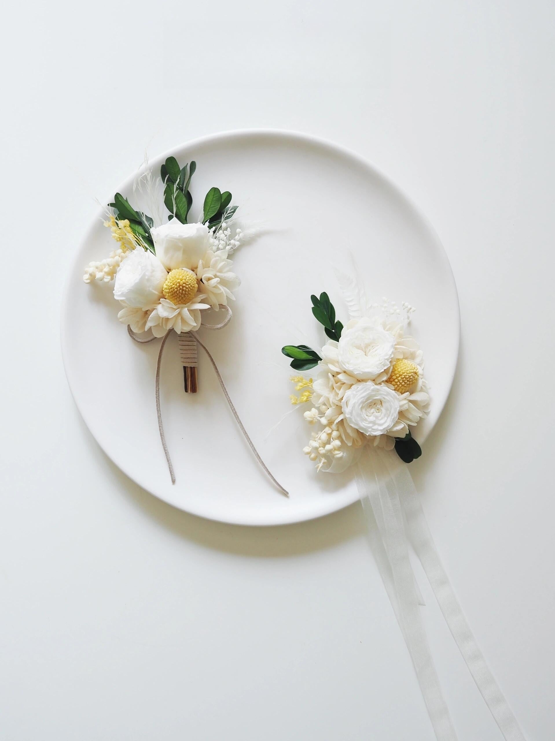 Cream ranunculus and craspedia boutonniere with greenery for weddings
