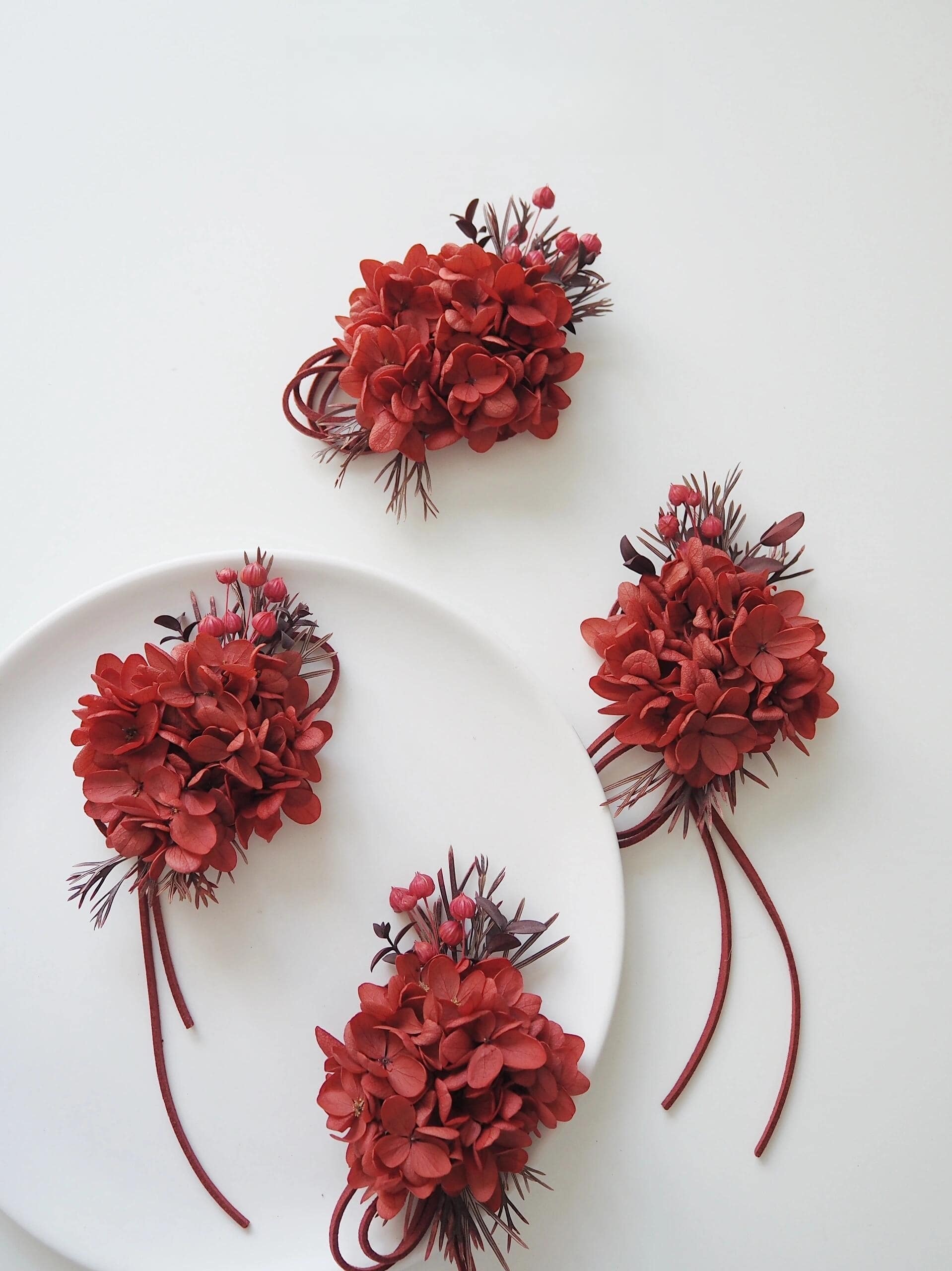 Elegant wedding corsage with preserved deep red hydrangeas and berries
