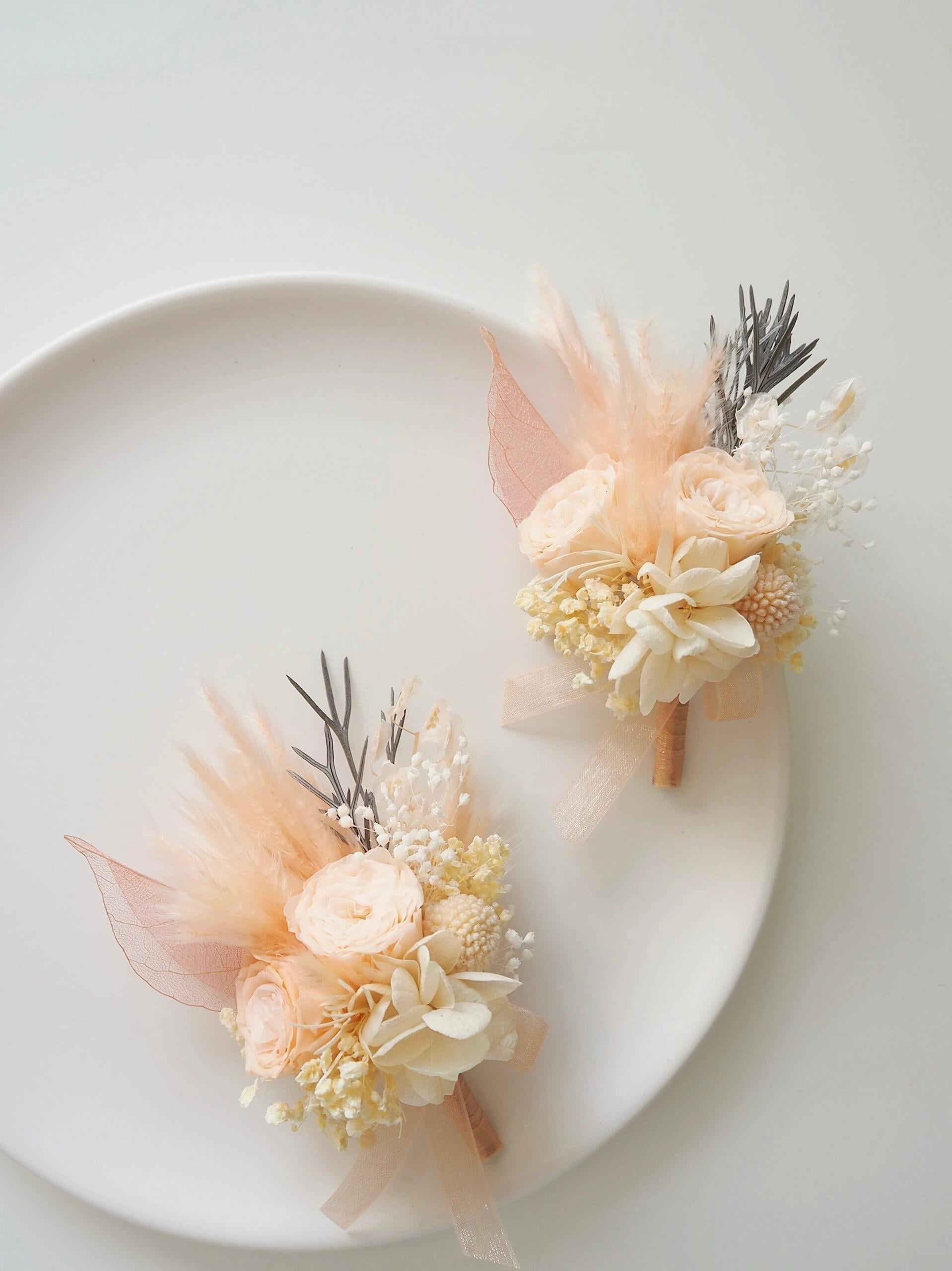 Wedding boutonniere with preserved peach ranunculus and greenery
