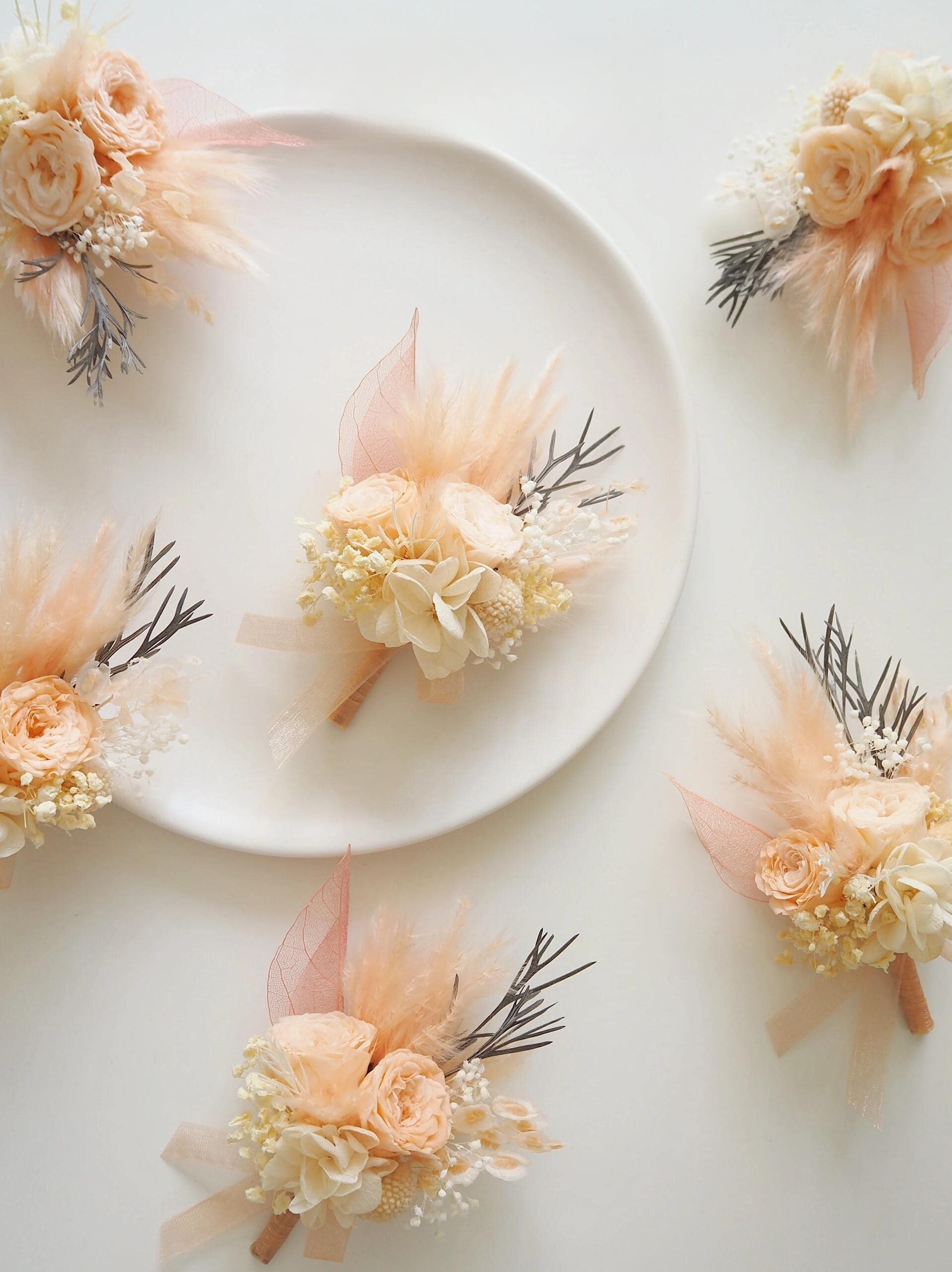 Soft peach and ivory preserved flower boutonniere for groomsmen
