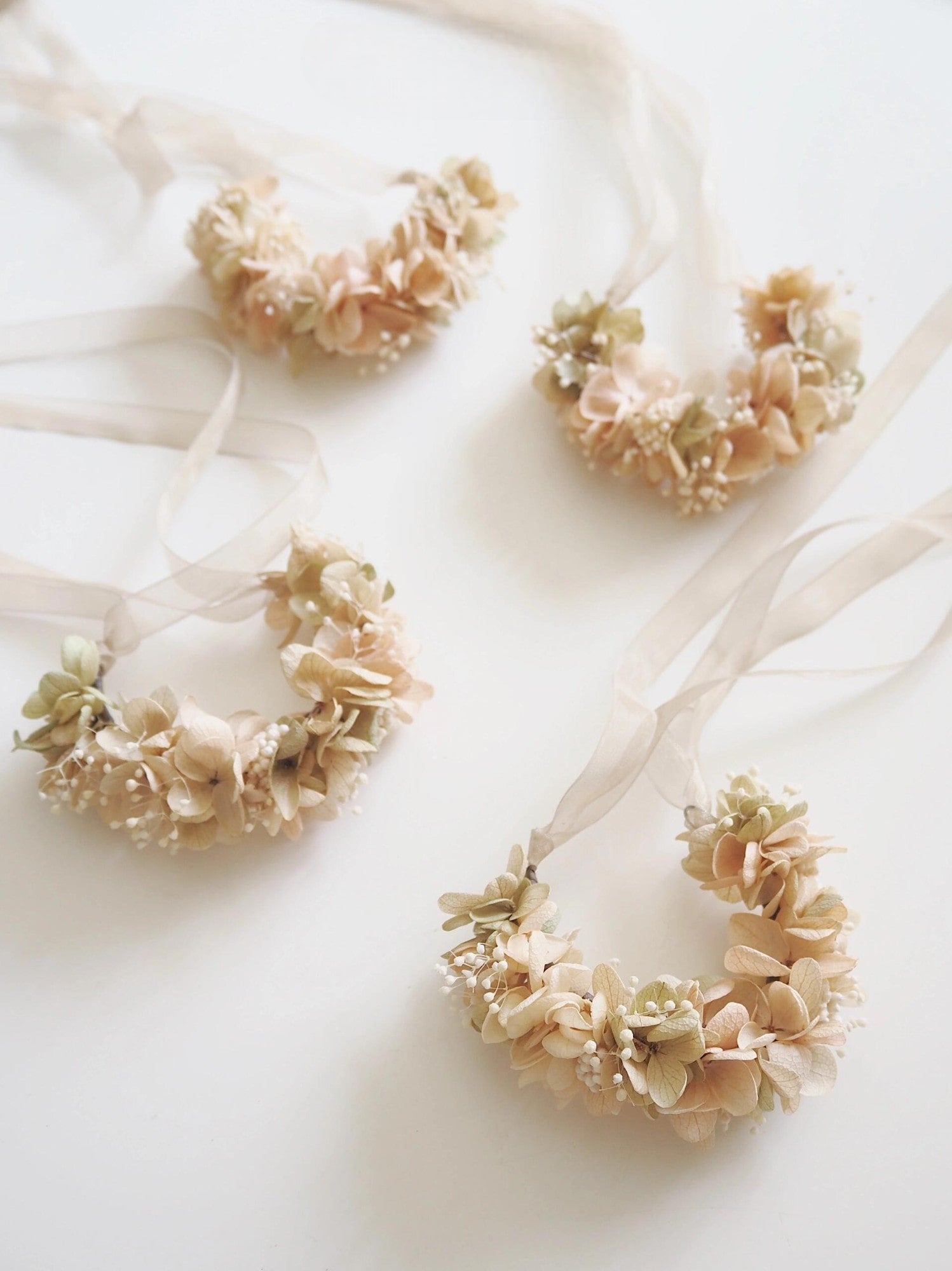 Beige hydrangea wrist corsage with white baby's breath on a white plate.
