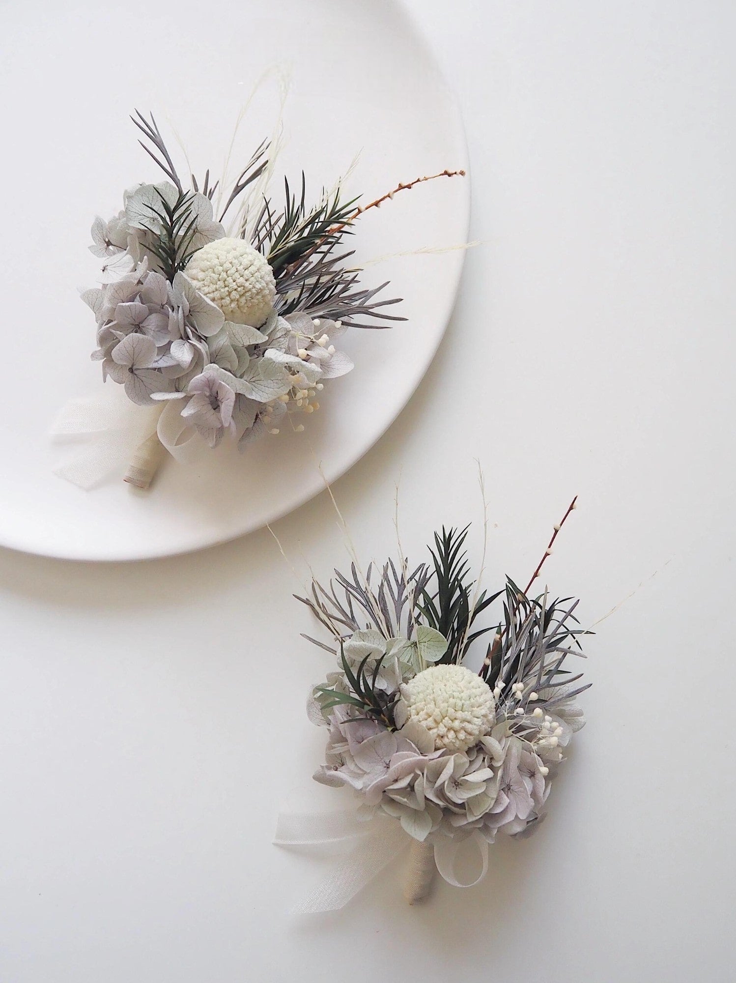 Close-up of ivory and gray floral boutonniere for weddings.
